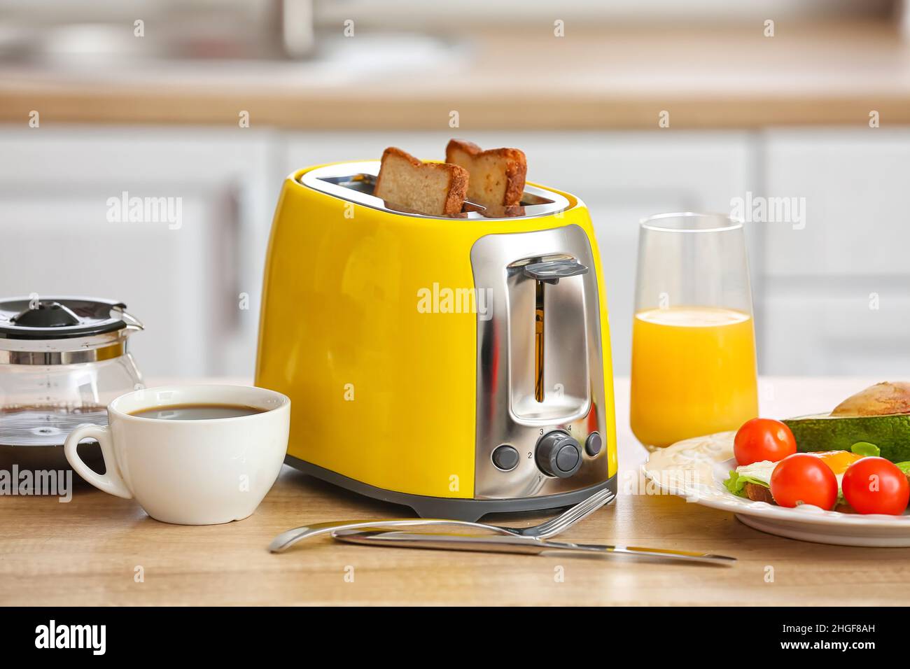 Yellow toaster with tasty food and drinks on counter in kitchen Stock