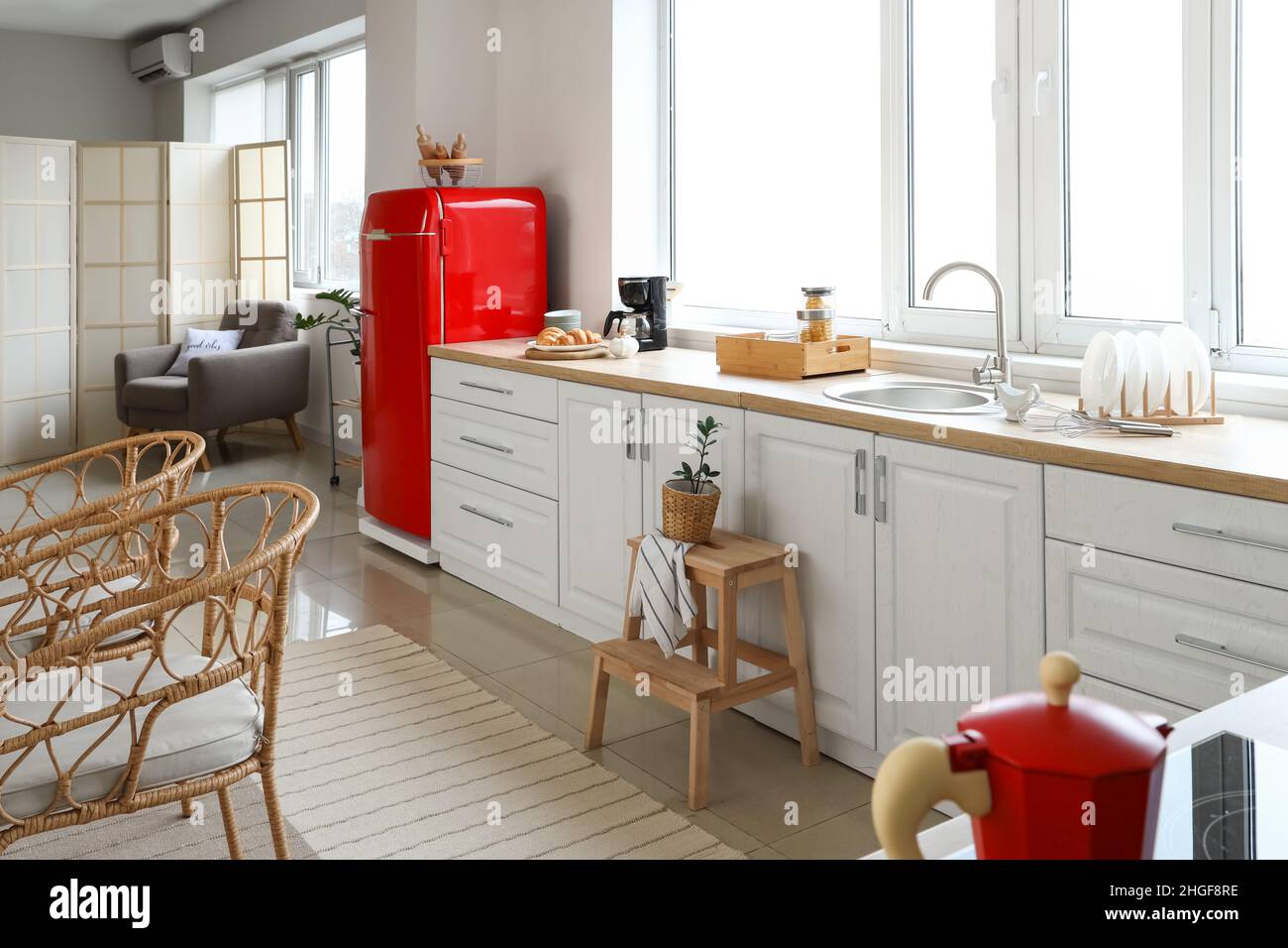 Interior of light modern kitchen with red fridge, white counters and ...