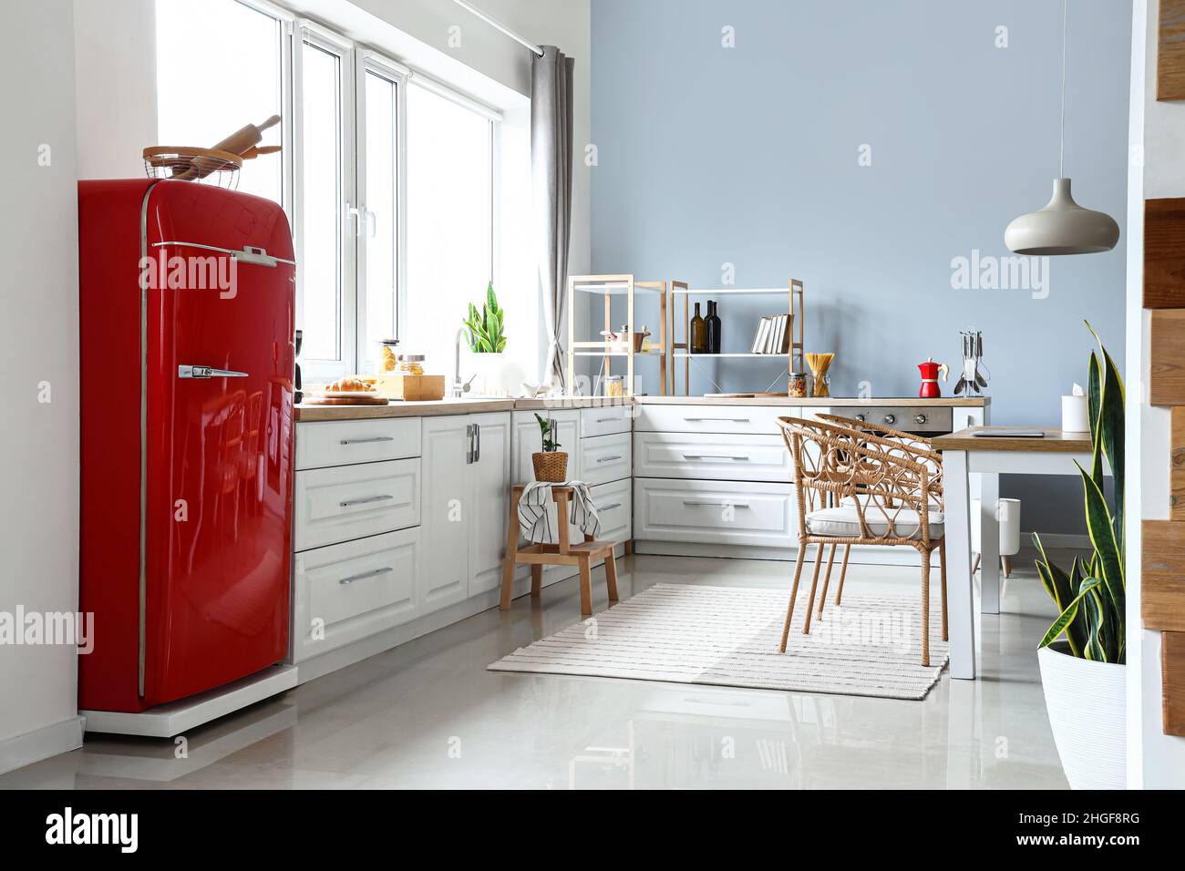 Interior of light modern kitchen with red fridge, white counters and ...