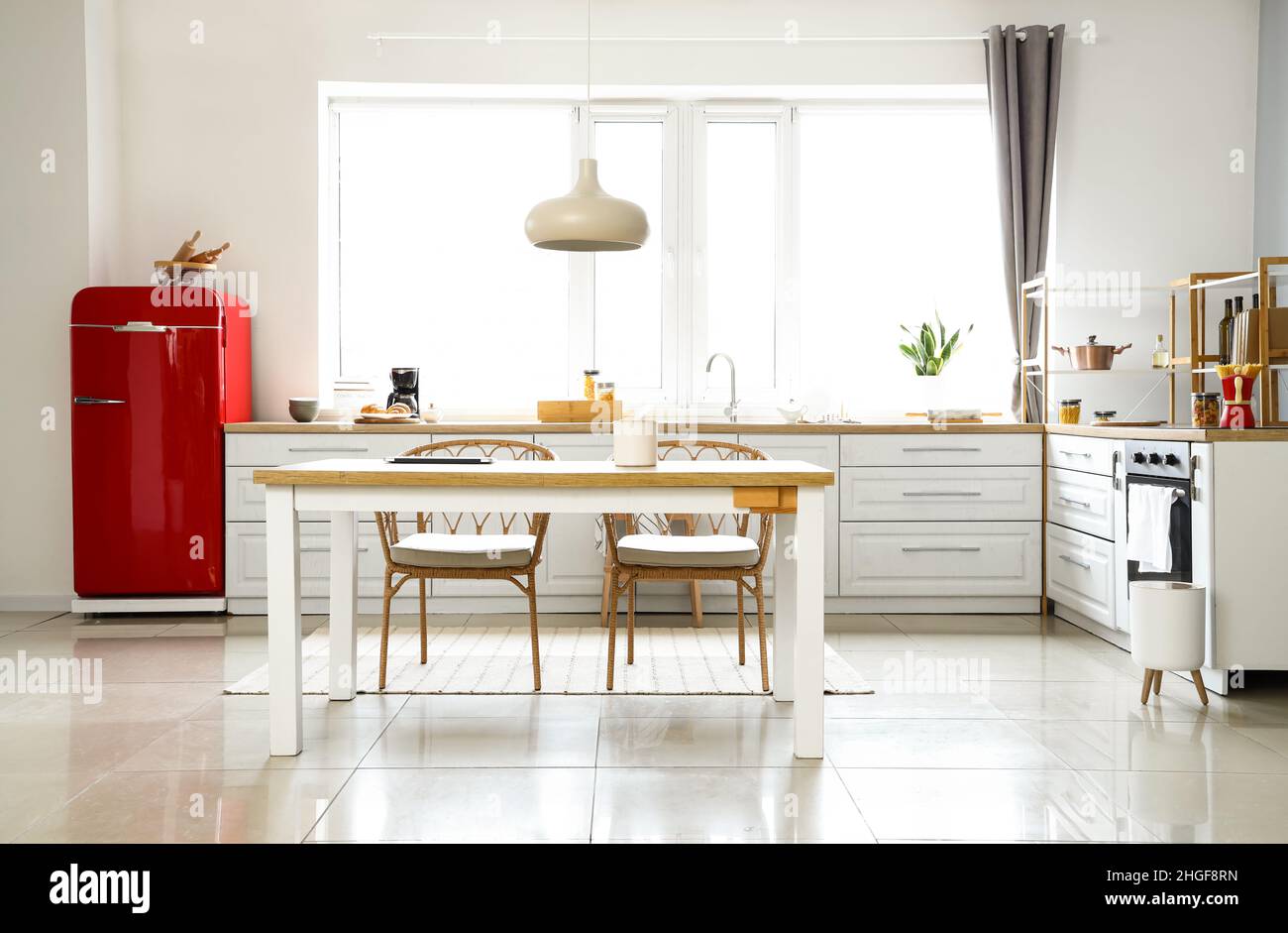 Interior of light modern kitchen with red fridge, white counters and ...