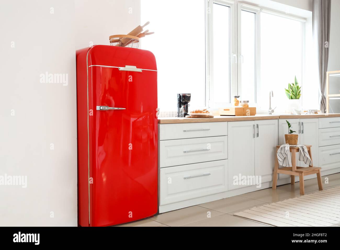 Interior of light modern kitchen with red fridge, white counters and ...