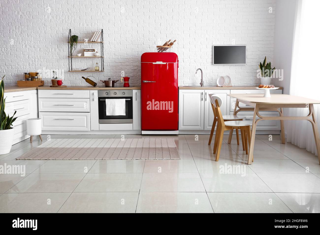 Interior of light kitchen with red fridge, white counters and dining ...