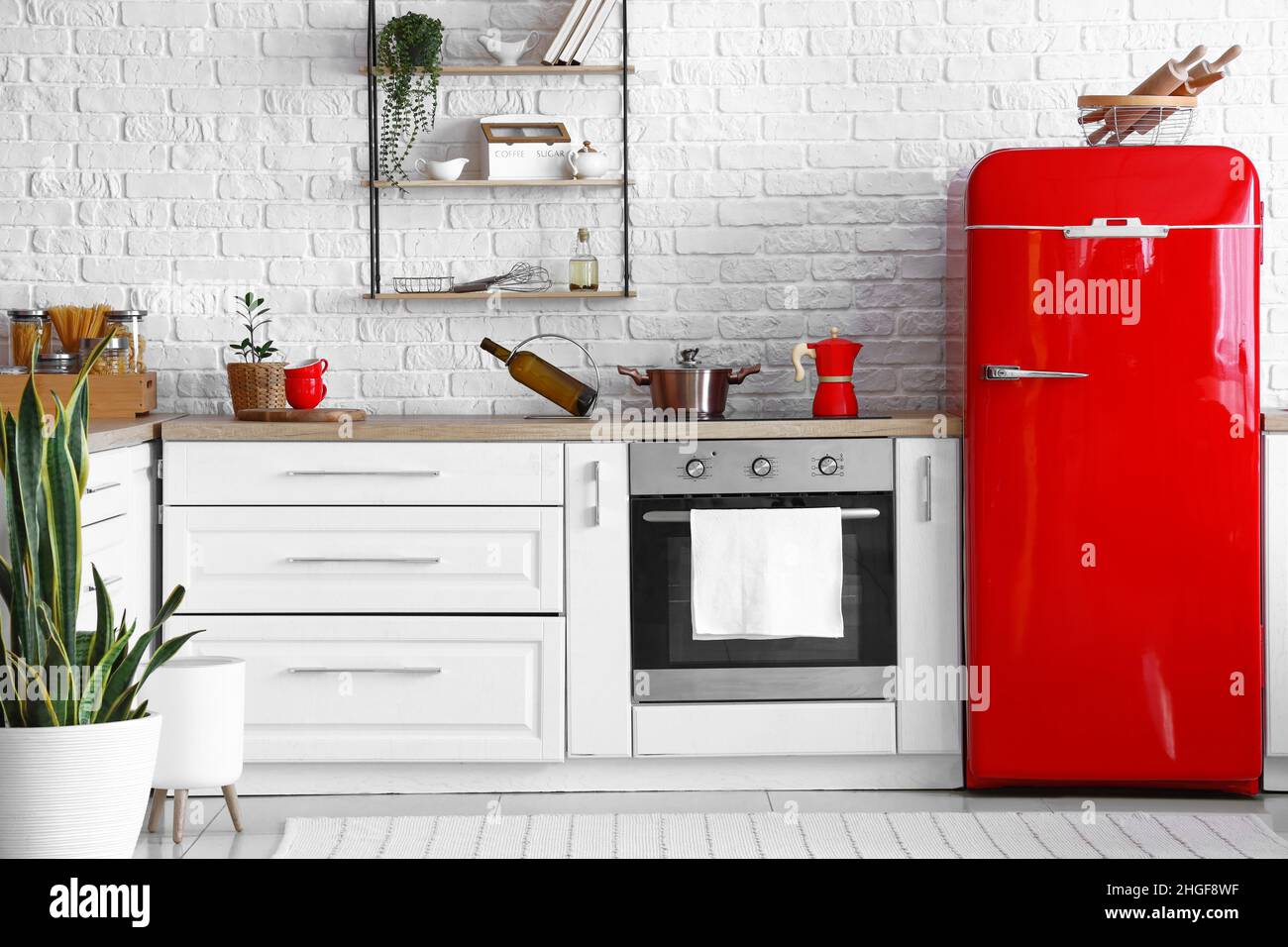 Interior of light kitchen with red fridge, white counters and oven ...