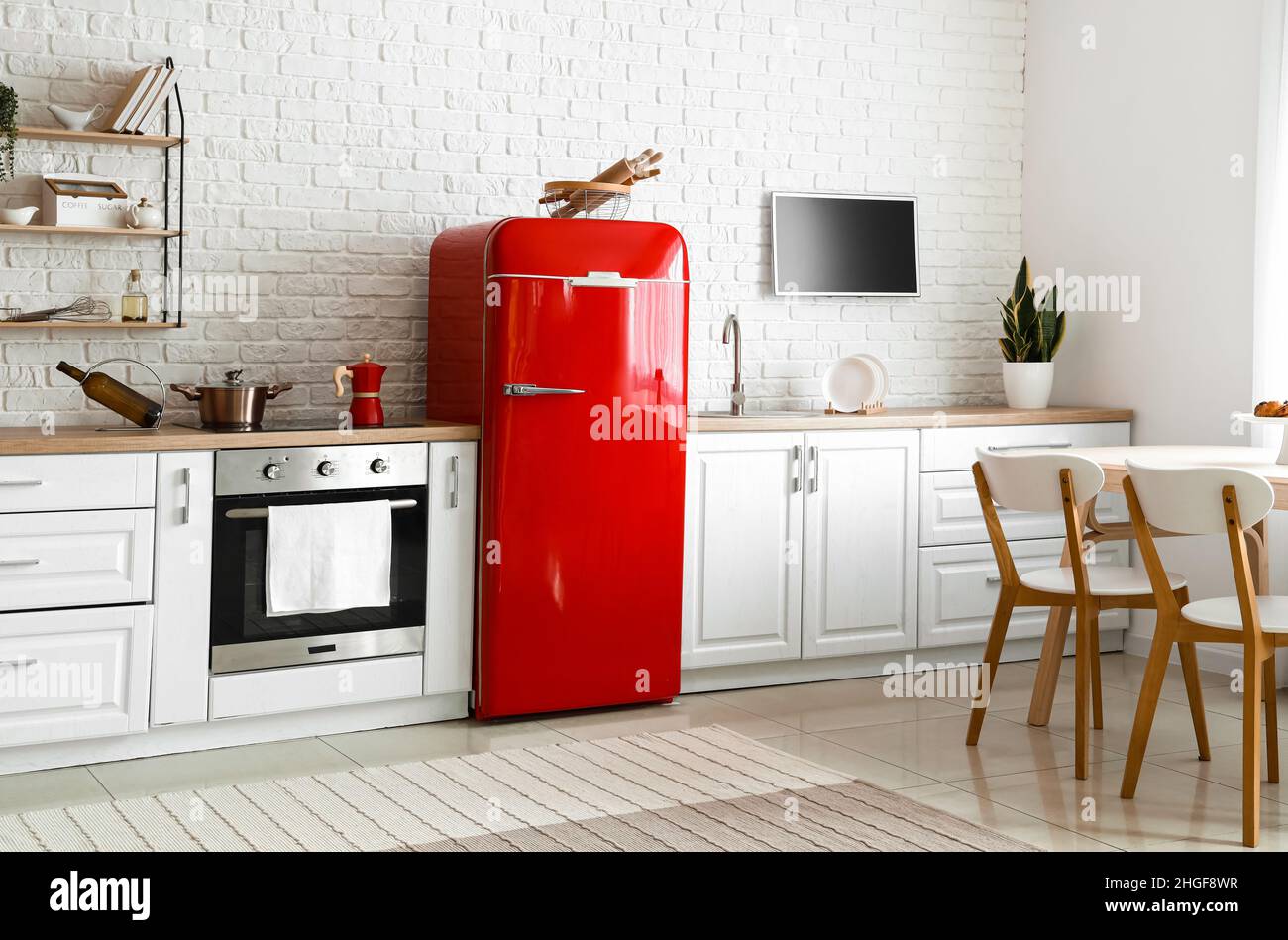 Interior of light kitchen with red fridge, white counters and dining ...