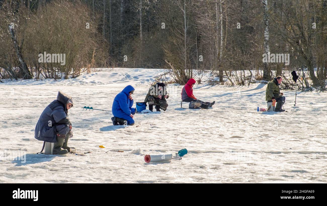 Ice fishing. Anglers catching fish in early spring on the last ice. Zaslavl water reservoir. Belarus. Minsk region. Stock Photo