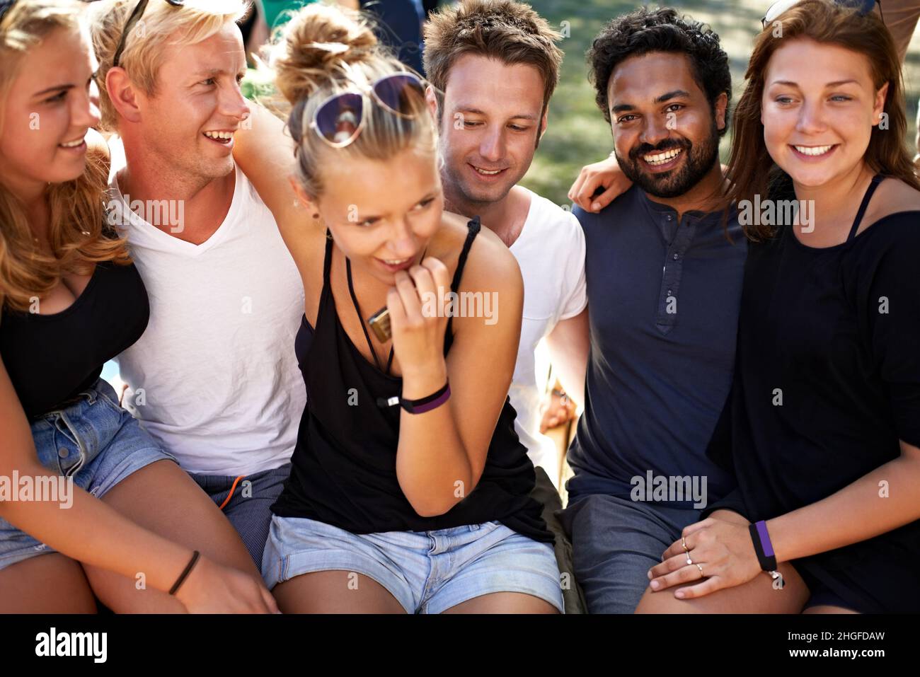 Casual and cool crew. A group of friends sitting together arm in arm ...