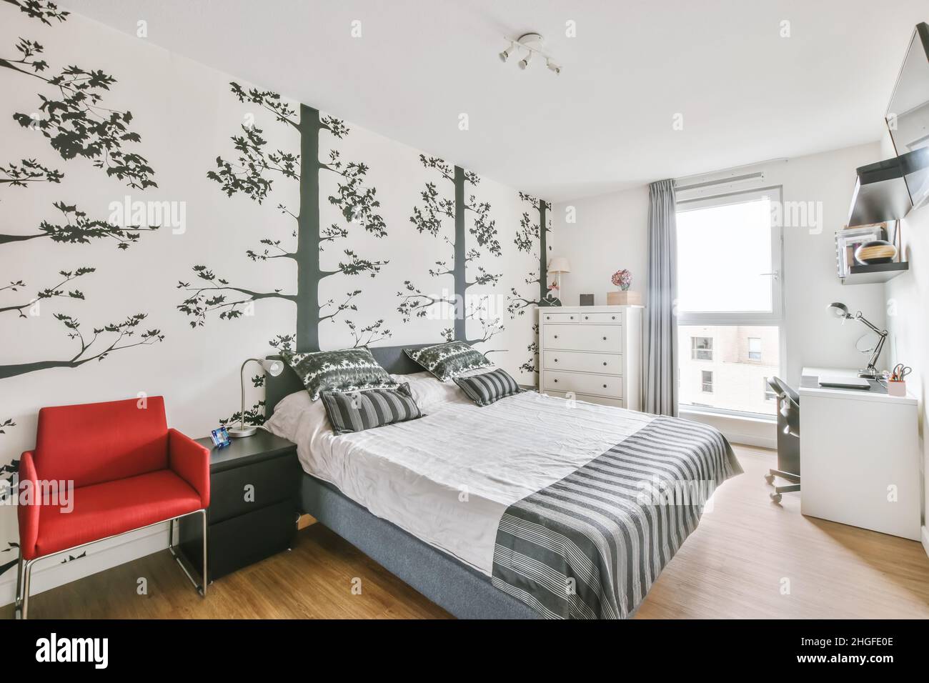 Stylish bedroom with lovely wallpaper and soft bed with decorative pillows Stock Photo