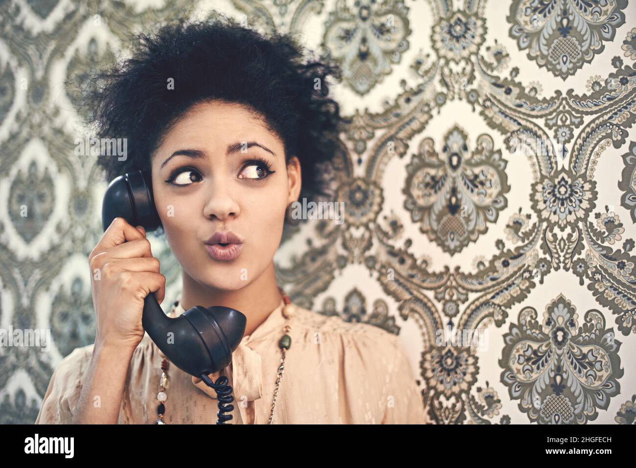 Oh, really. Studio shot of a young woman in a vintage outfit talking on an old-fashioned telephone. Stock Photo
