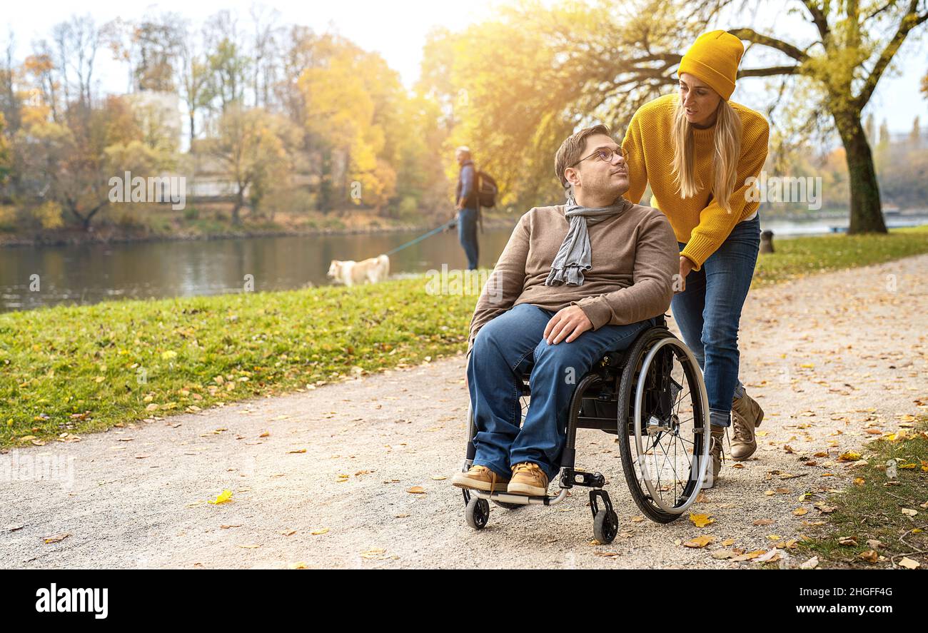 Woman and her friend in a wheelchair having stroll through the park at ...