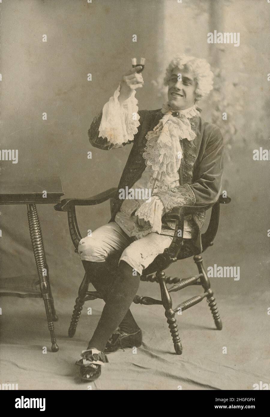 Antique circa 1910 photograph, man dressed in period 18th century fashion with breeches, stockings, lace cravat, wife, cuffs, and shoe buckles. SOURCE: ORIGINAL PHOTOGRAPH Stock Photo