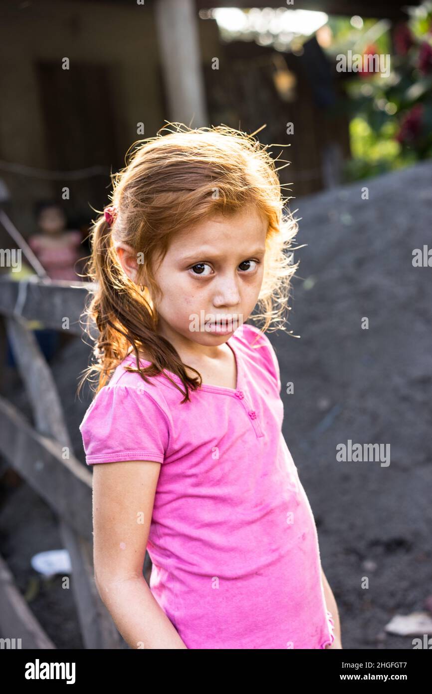 Young red haired Nicaraguan girl looks apprehensively at the camera in rural Jinotega Department, Nicaragua. Stock Photo