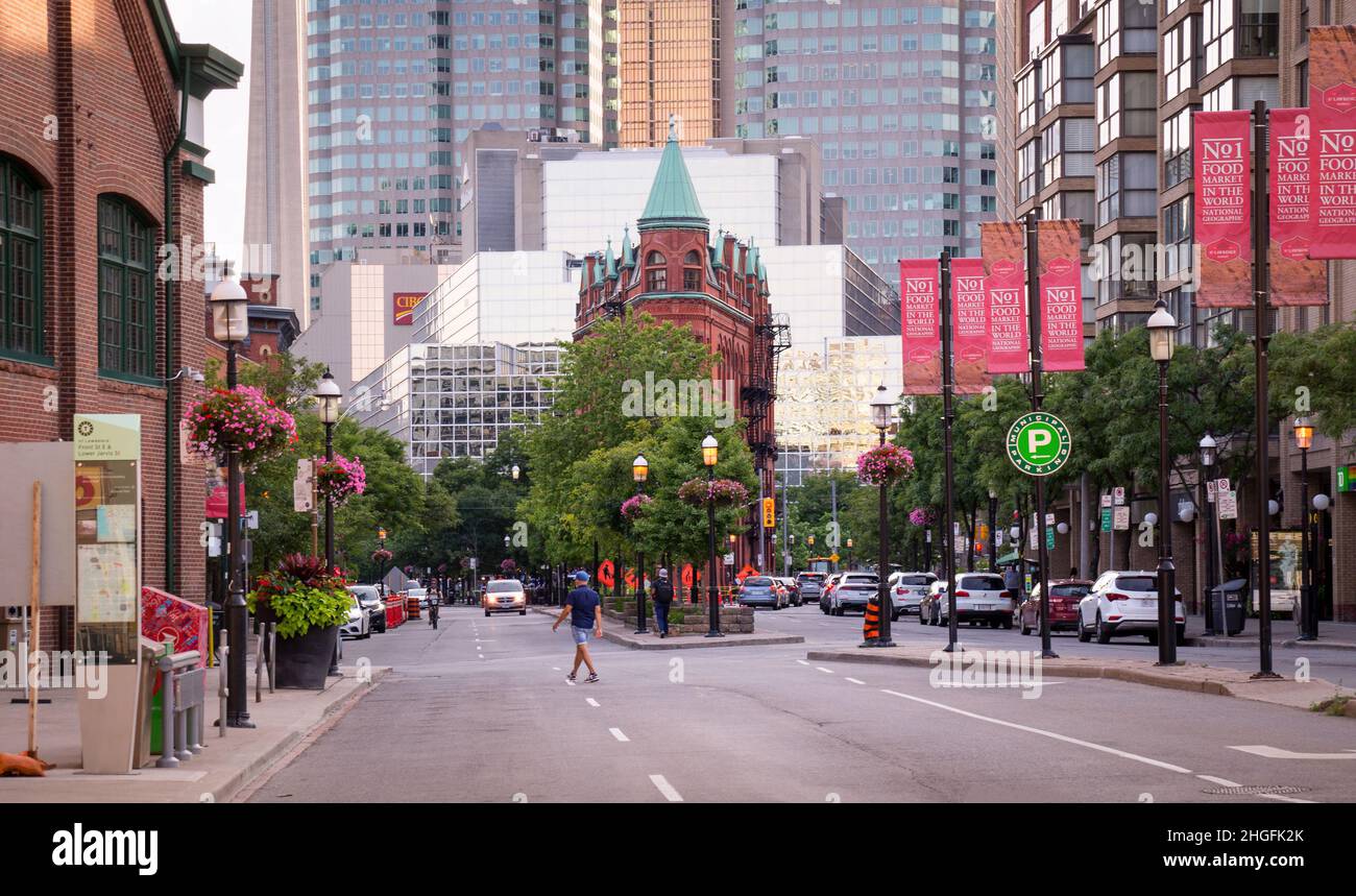 TORONTO, CANADA - 07 21 2020: Summer evening view along Front street with colorful flowerbeds, green trees, and Gooderham flatiron building befire Stock Photo