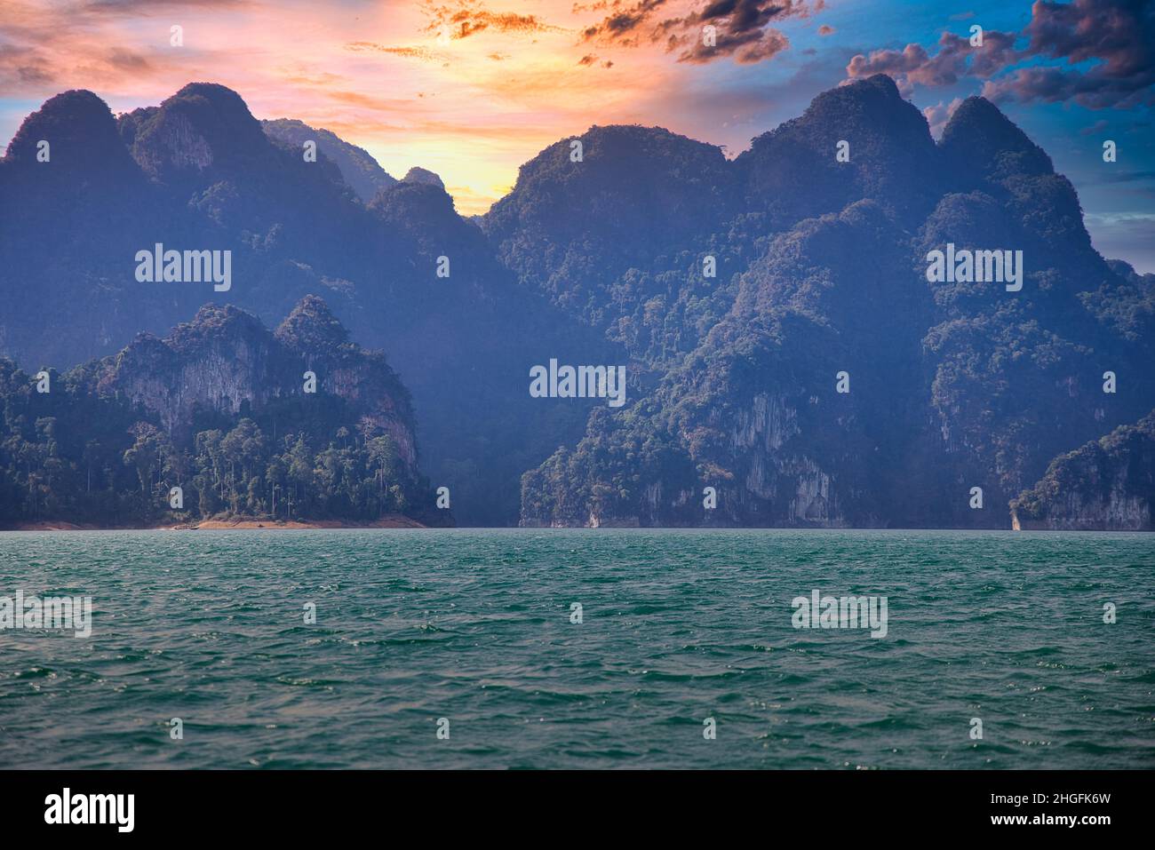 The stunning landscape with water and mountains at sunset of Khao Sok National Park in Thailand Stock Photo