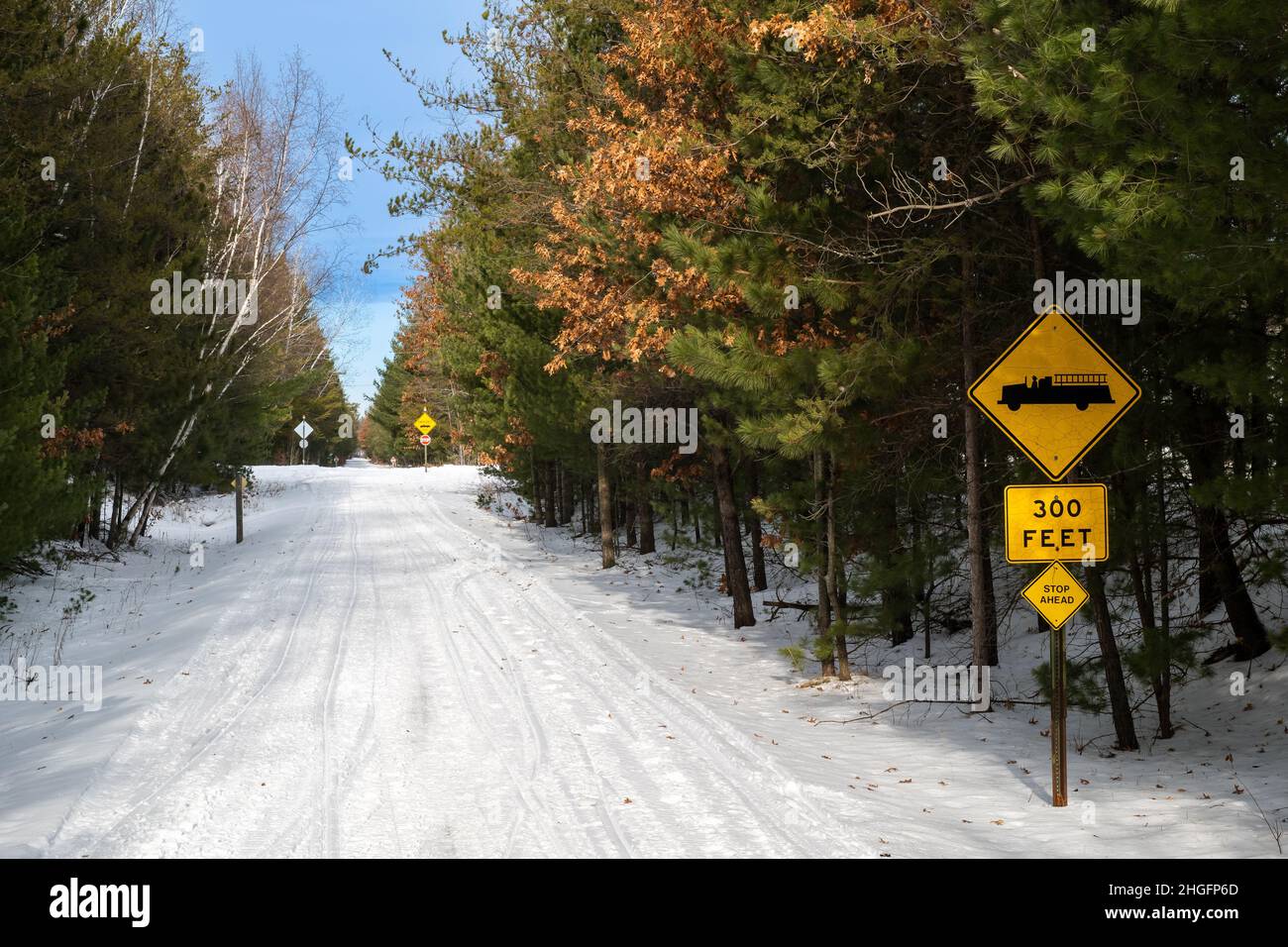 Groomed snow covered snowmobile and hiking trail through a forest in Central Minnesota with yellow signs. Paul Bunyan State Trail in Nisswa. Stock Photo