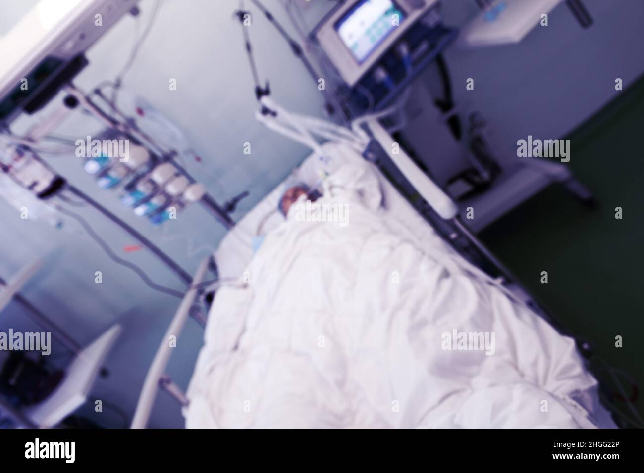 ICU ward interior with patient lying in bed, unfocused background. Stock Photo
