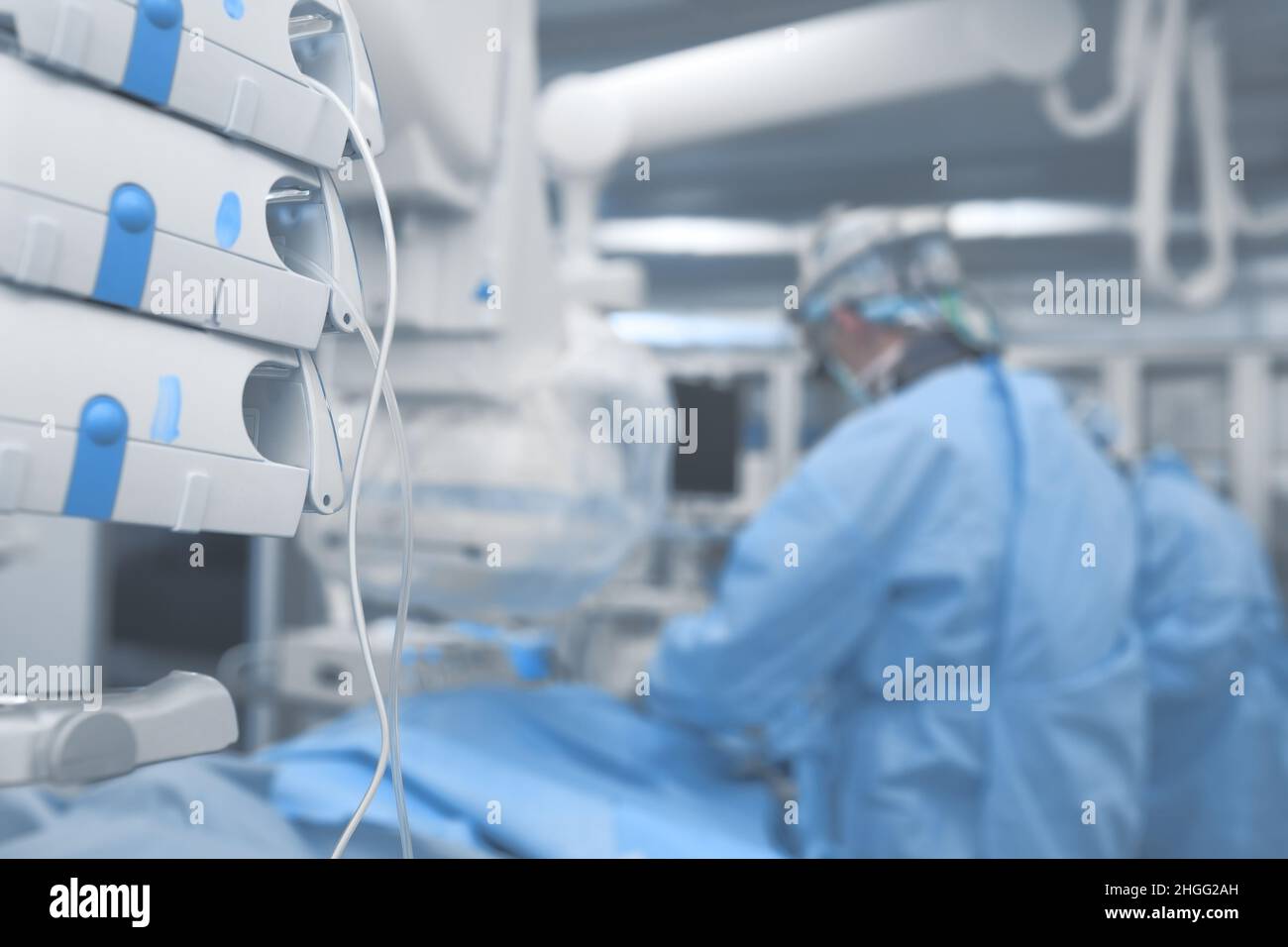 Operating room with working surgeons surrounded by modern equipment. Stock Photo