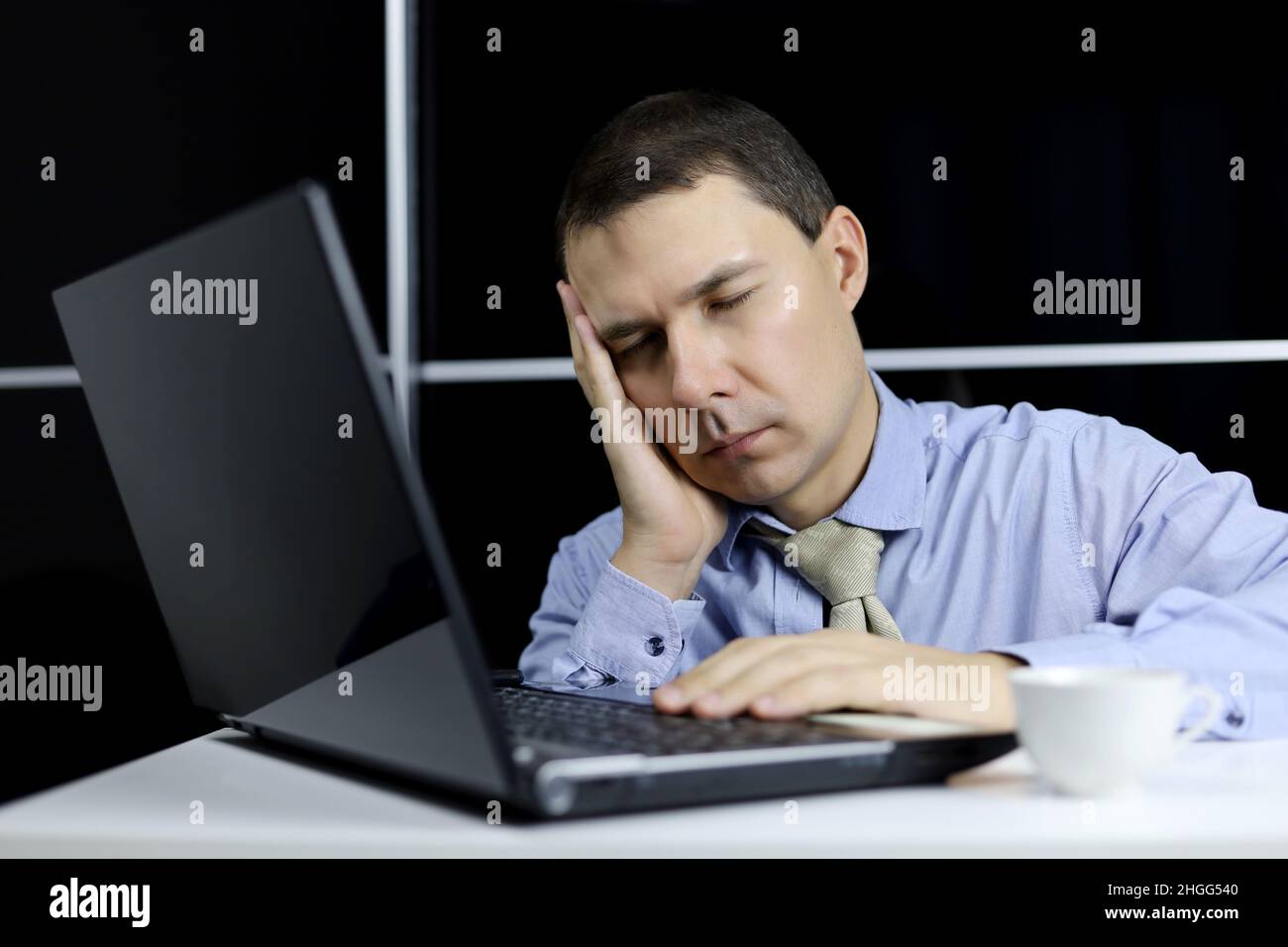 Man in the sleeping at laptop. Office worker after sleepless night, tired of overworking concept, chronic fatigue at workplace Stock Photo