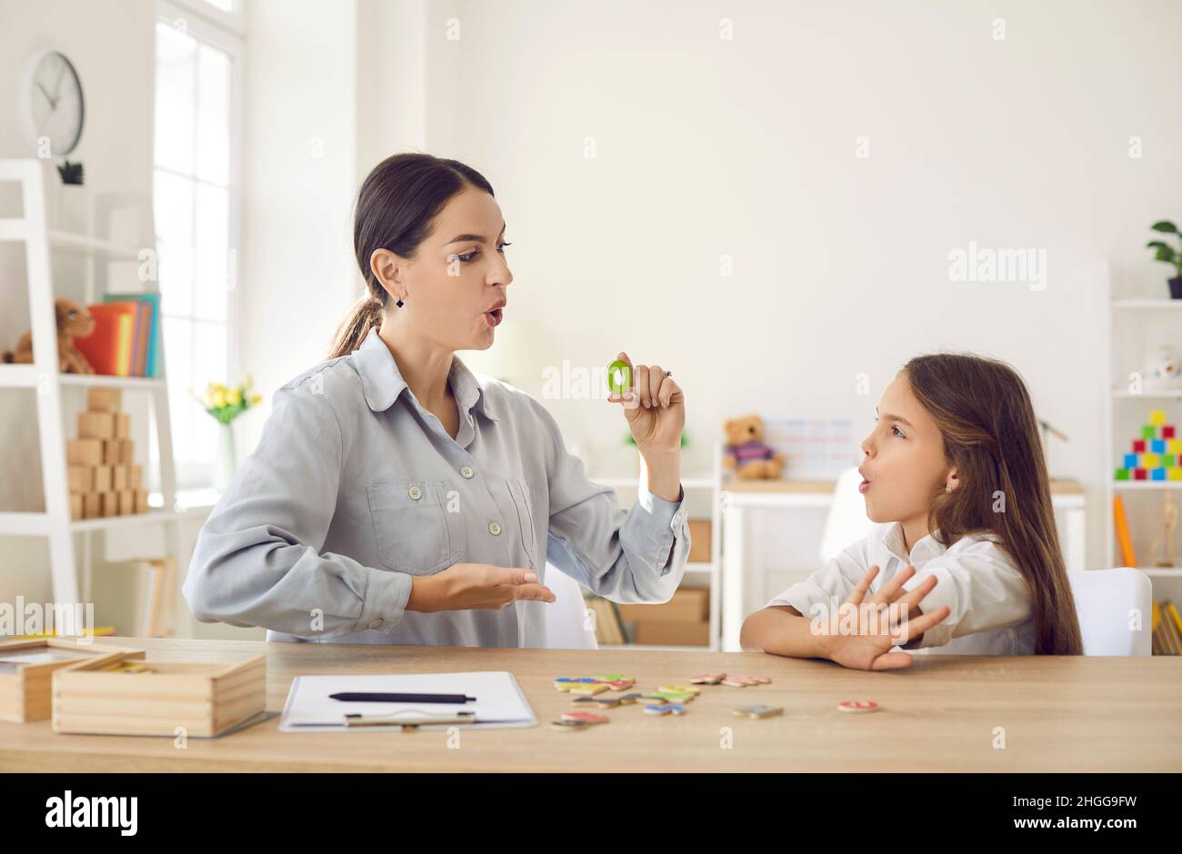 Girl of primary school age practices correct pronunciation with female speech therapist. Stock Photo