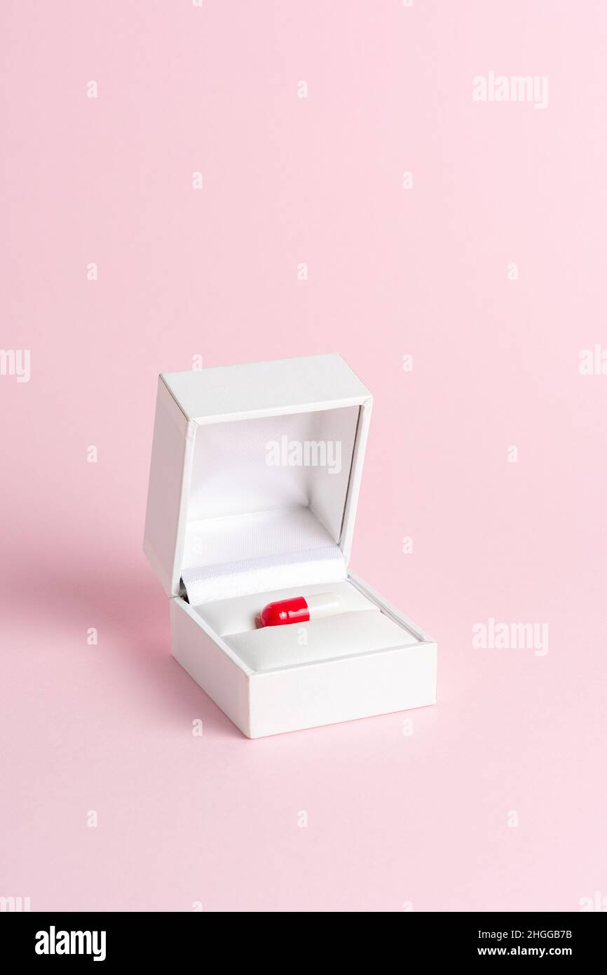 Minimal composition made of red pill and engagement ring box. Creative concept. Stock Photo