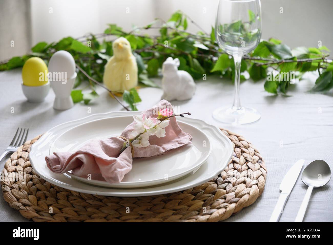 Easter table setting with yellow chick,decorations, fresh flowers and eggs. Elegance dinner. Close up. Stock Photo