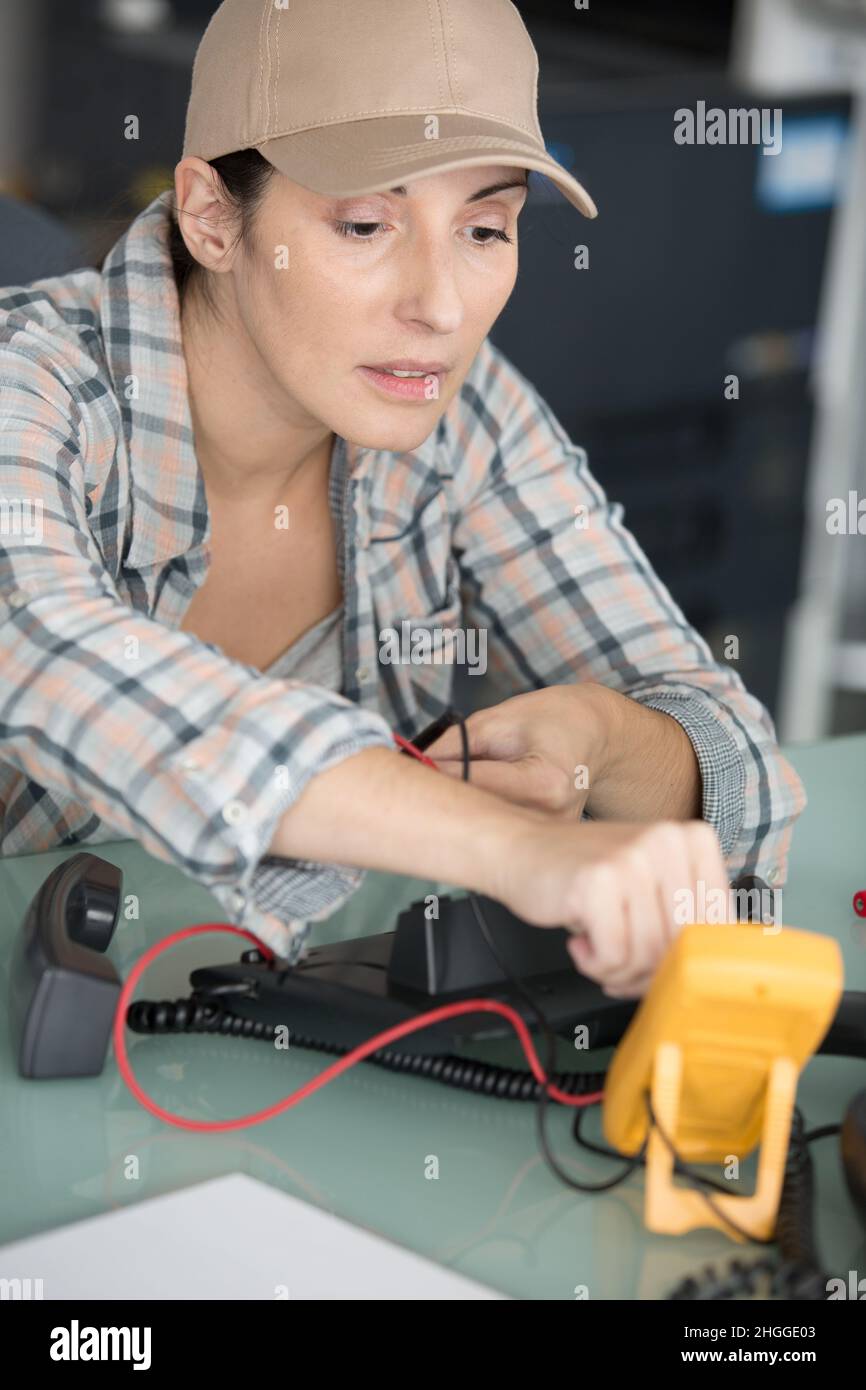 female electrician using multimeter to check telephone voltage Stock
