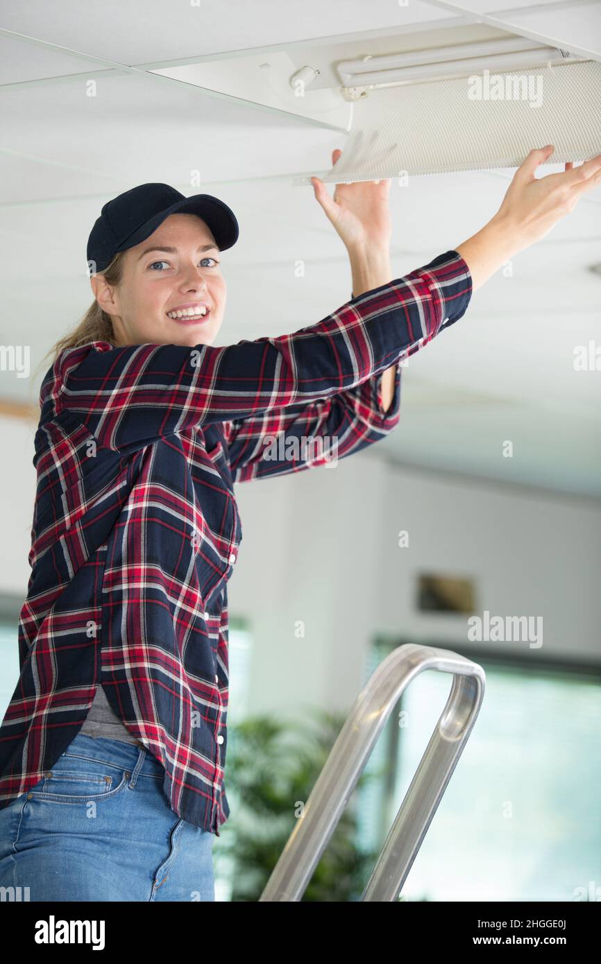 woman on ladder fitting light bulb in new house Stock Photo - Alamy