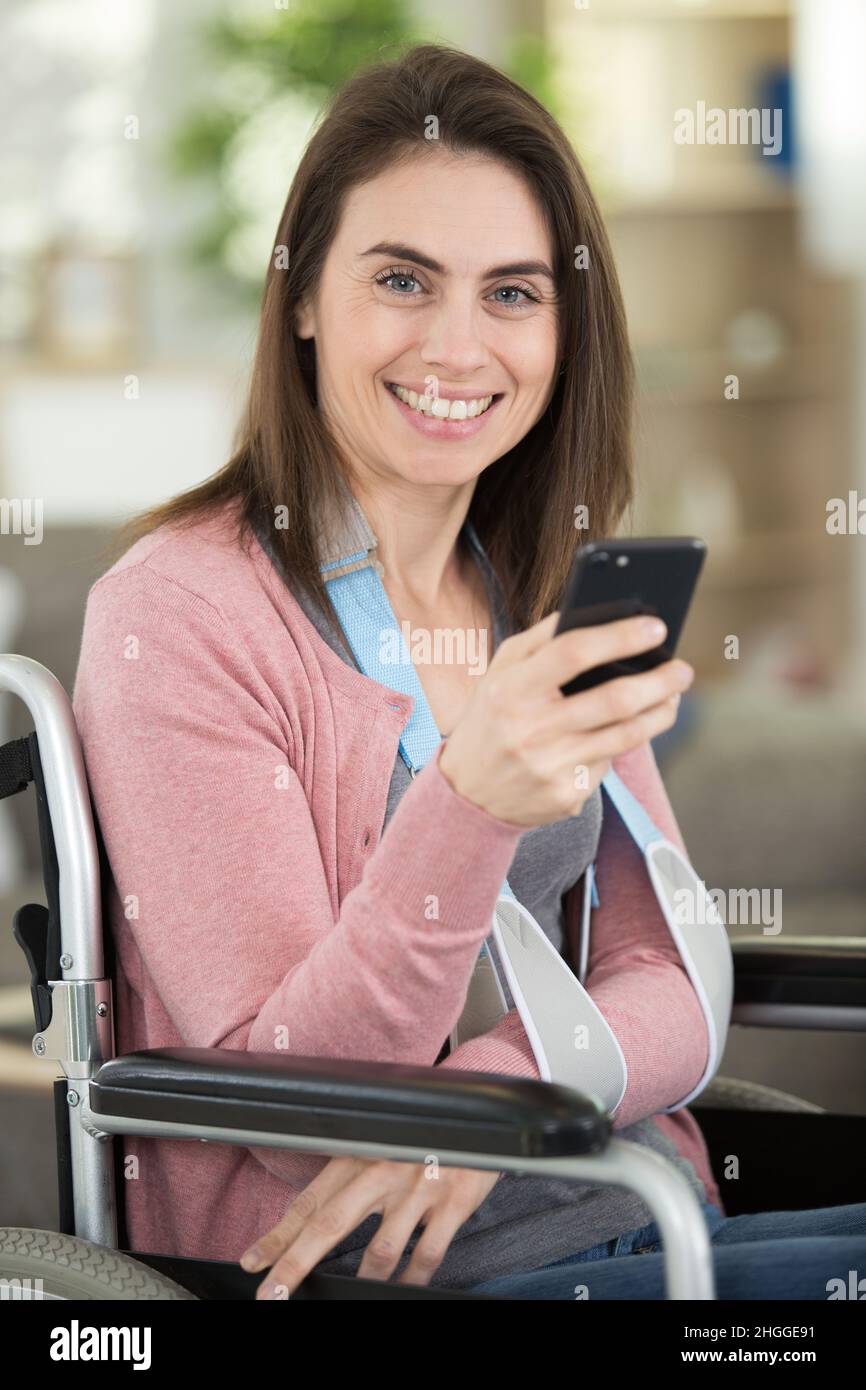 woman in wheelchair with arm in a sling using smartphone Stock Photo ...