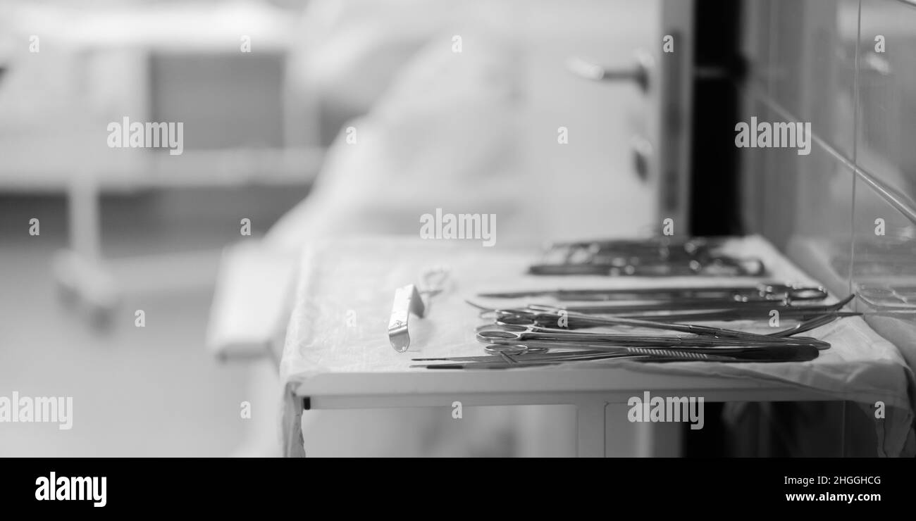 Sterile surgical instruments on the table in the hospital. Selective focus. Black and white photo. Copy space. Stock Photo