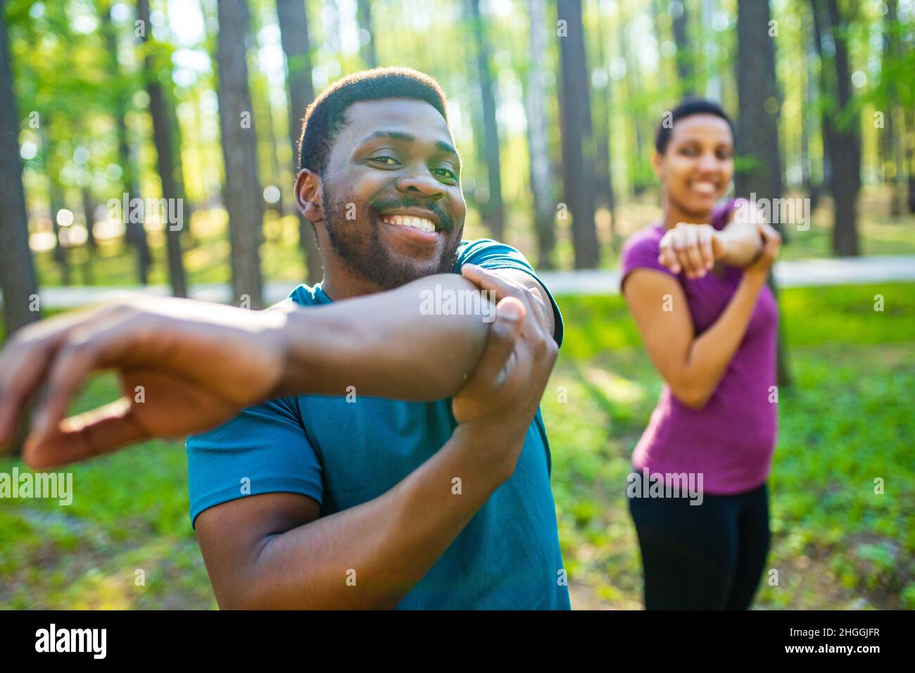 Young man and beautiful woman doing stretching exercises outdoors Stock Photo