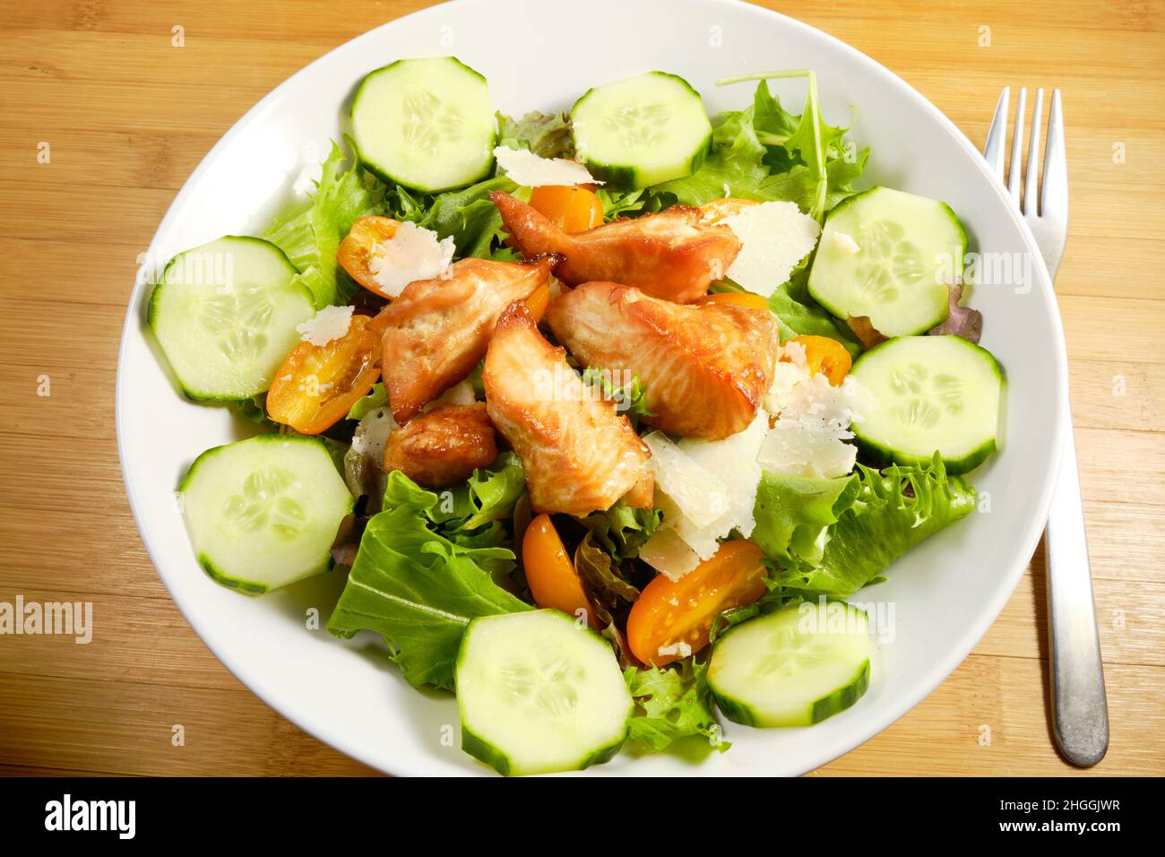 Fresh Salad with grilled cubes of teriyaki Salmon, cheese chunks on bed of spring mix lettuce with cucumber and tomatoes Stock Photo