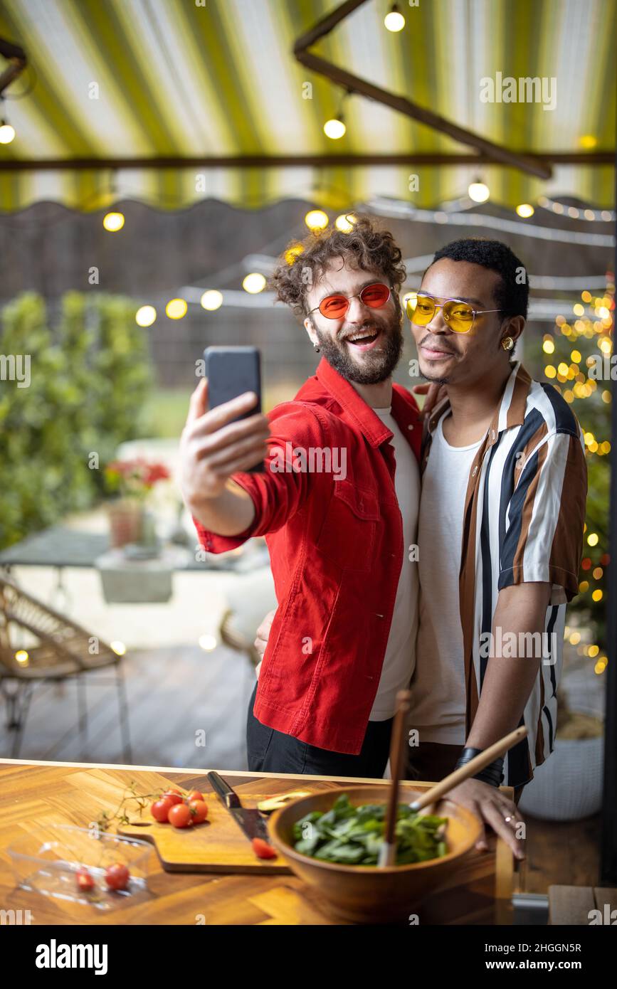 Two brightly dressed stylish guys taking selfie on phone indoors Stock Photo