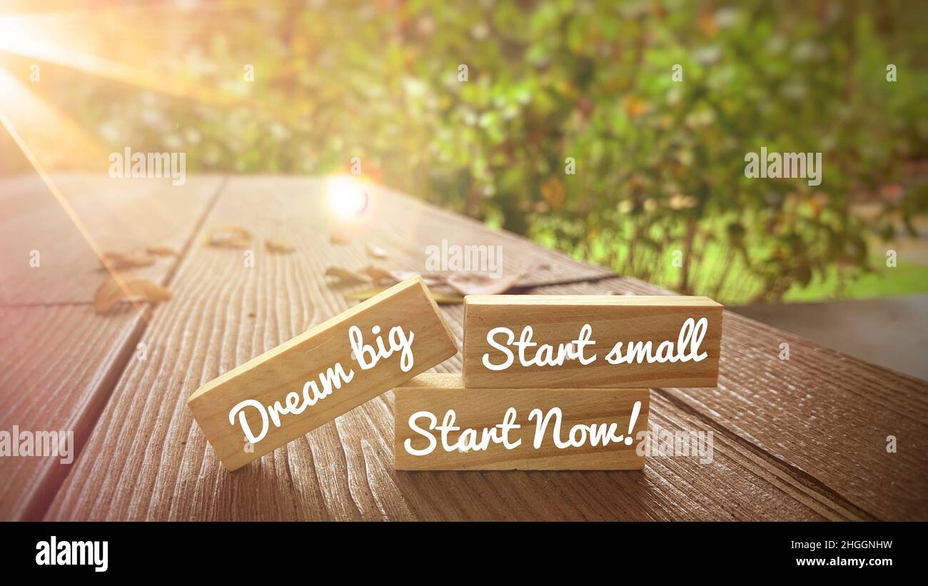 Motivational and Inspirational quote - Dream big, start small and start now text on wooden blocks with bright shining light. Motivational concept. Stock Photo