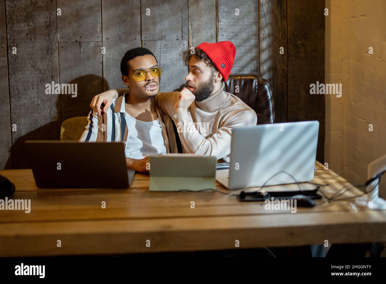 Gay couple working on computers at home office Stock Photo