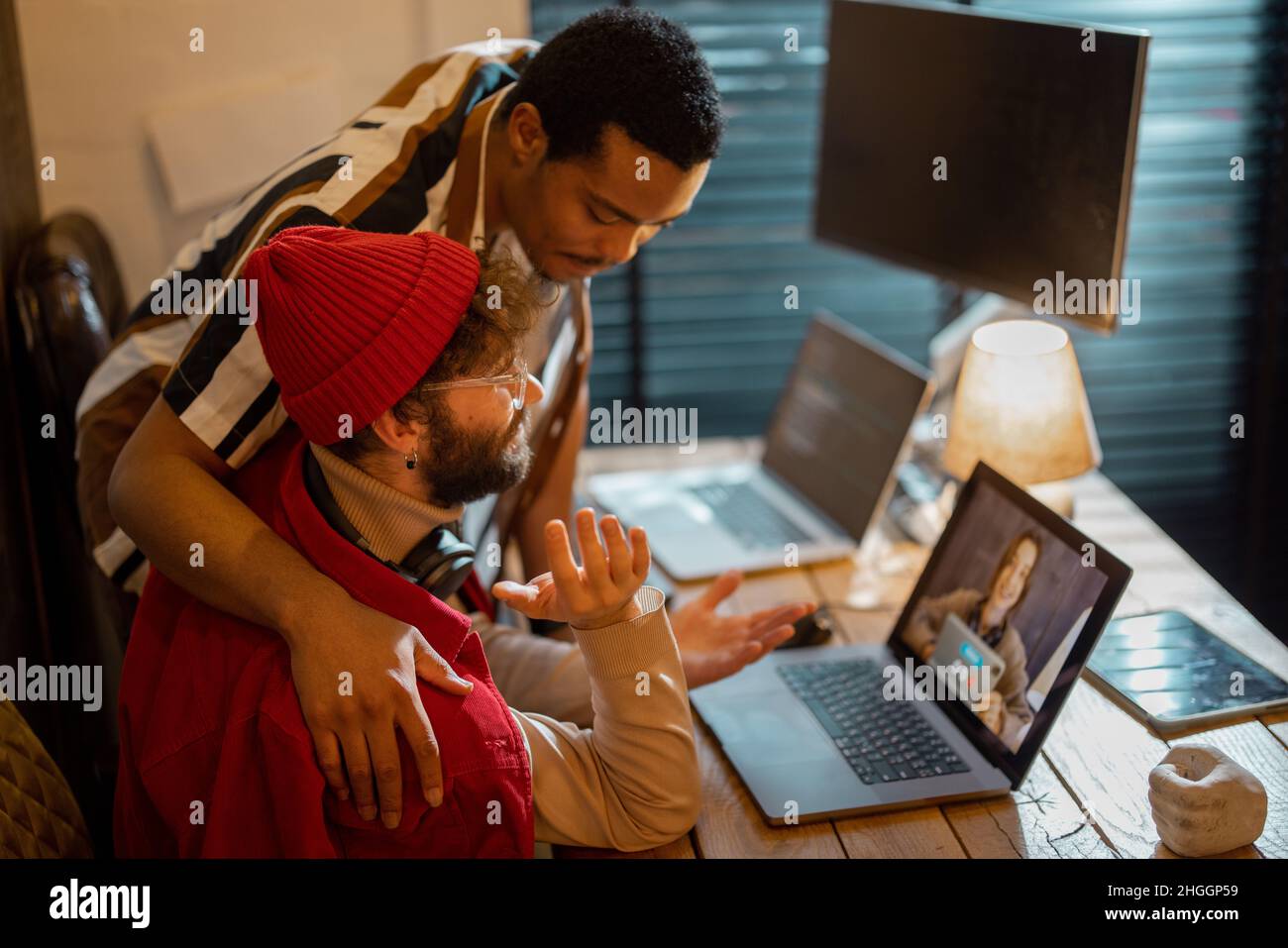 Stylish gay couple having video call with female colleague Stock Photo