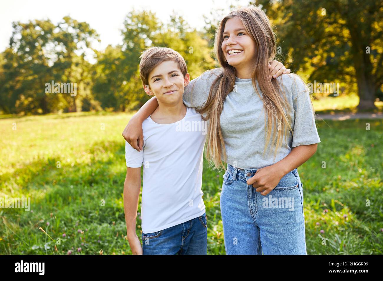 Brother and sister as happy siblings side by side in the park on