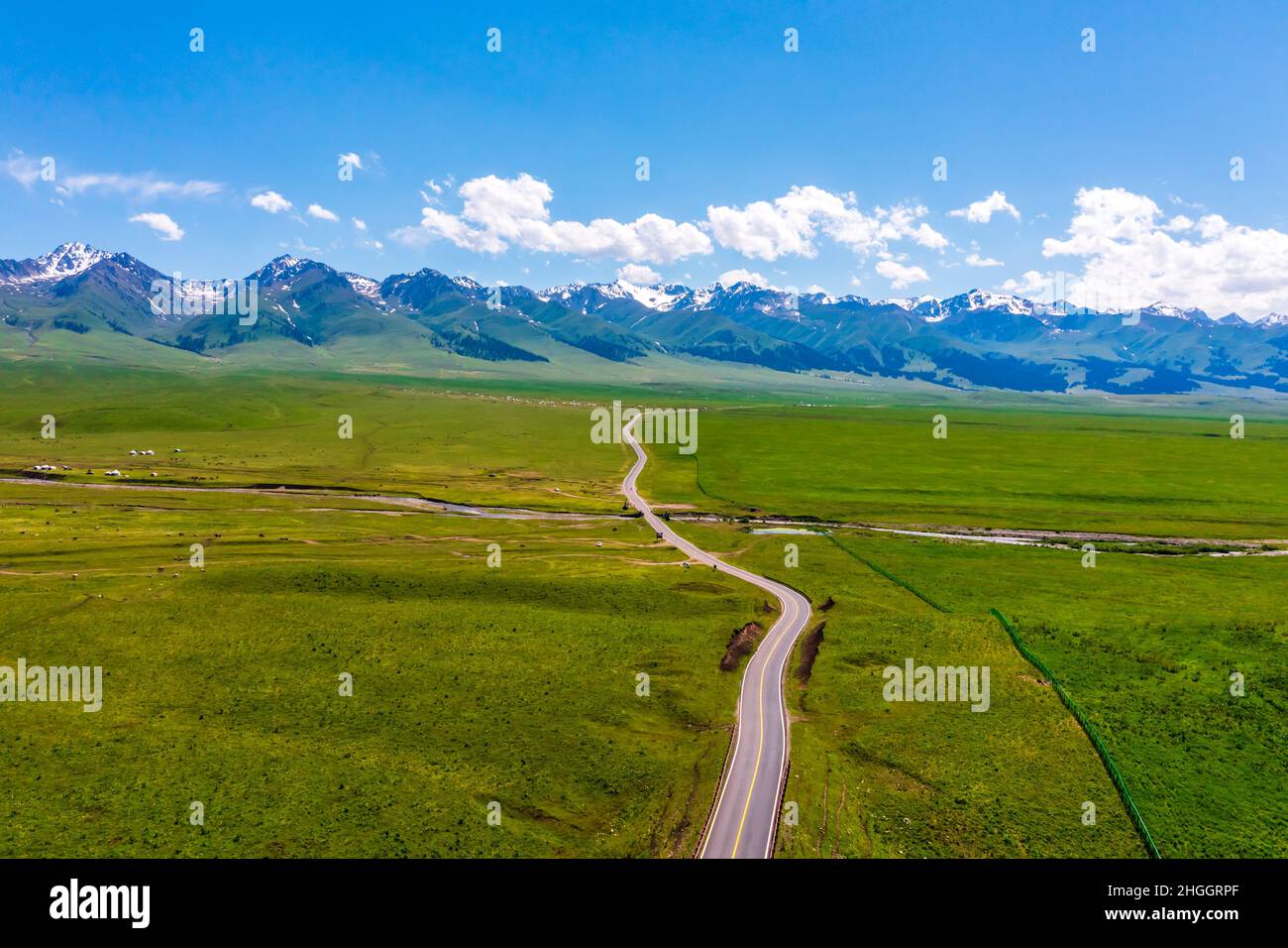 The road leads to distant mountains.Beautiful grassland and mountain scenery in Nalati grassland,Xinjiang,China. Stock Photo