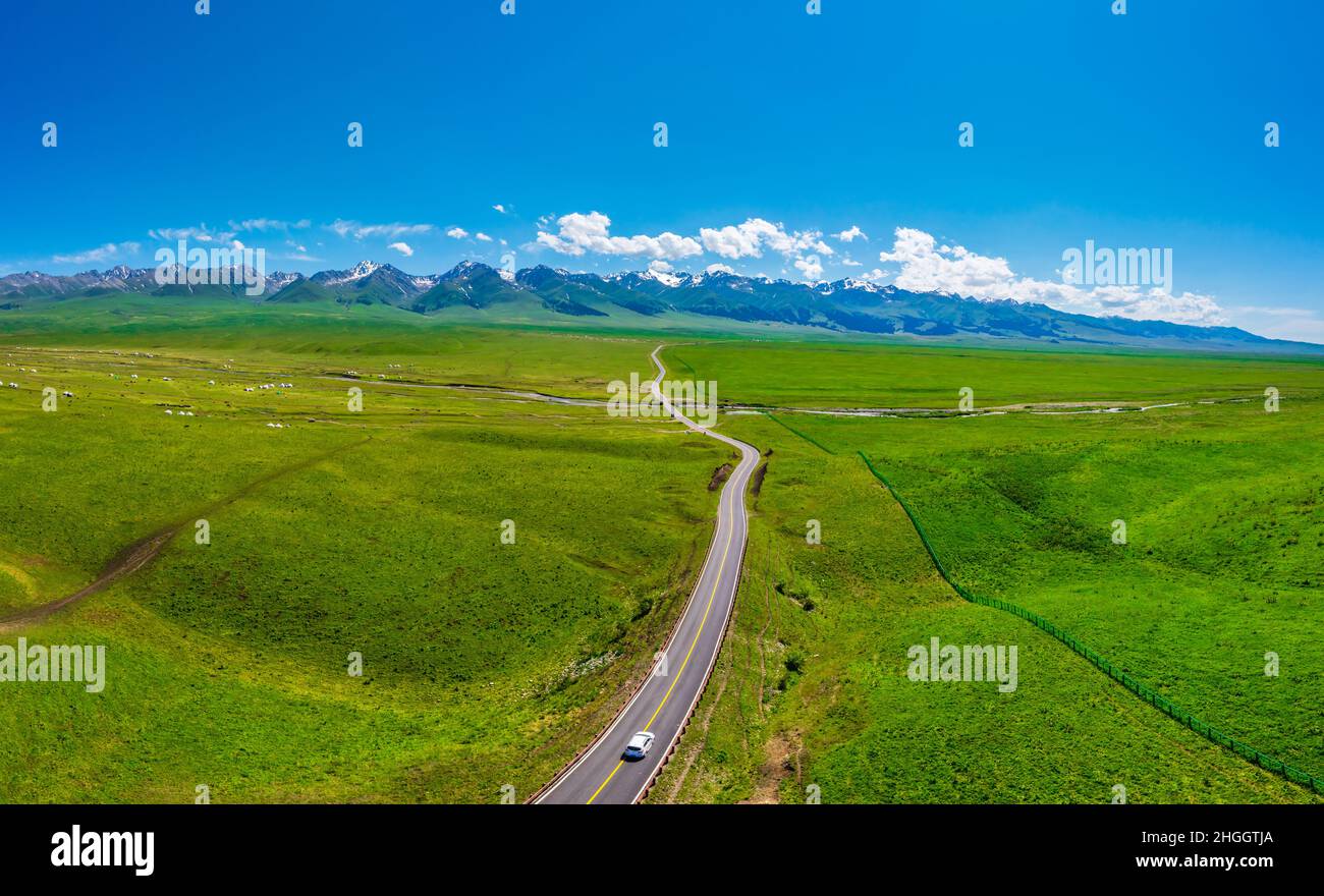 The road leads to distant mountains.Beautiful grassland and mountain scenery in Nalati grassland,Xinjiang,China. Stock Photo