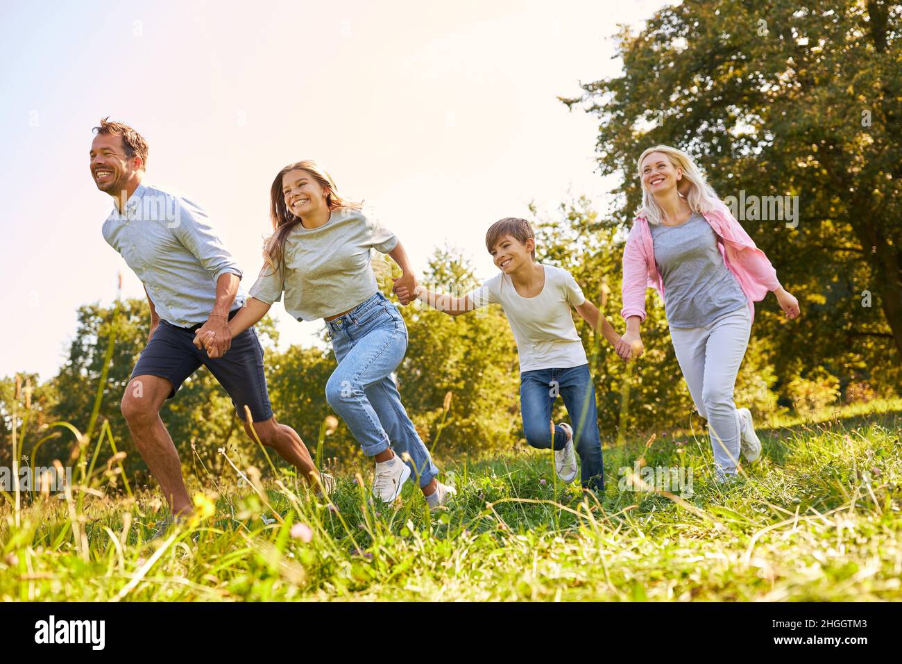 Happy family with two children running holding hands in park in summer ...