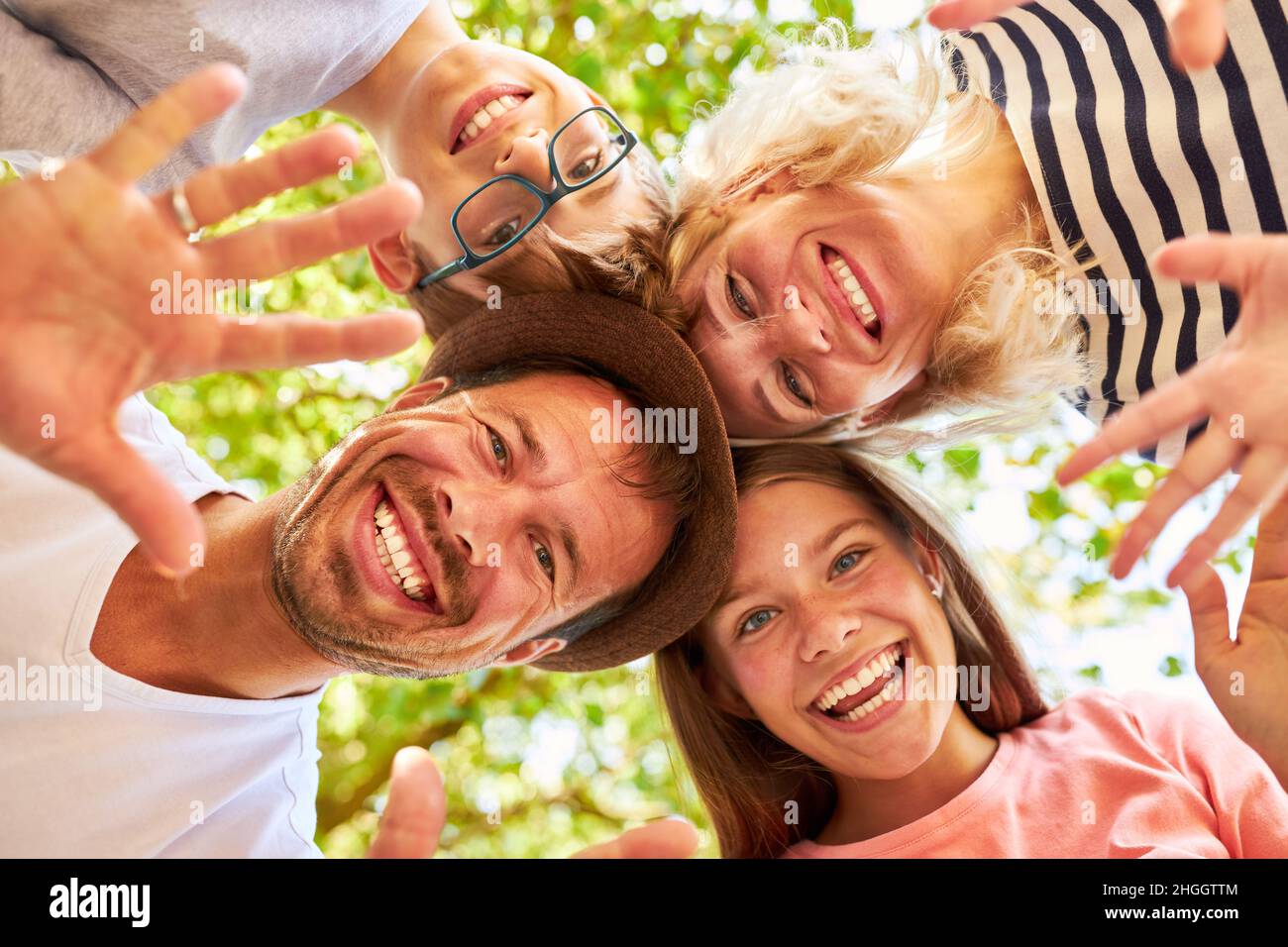 Family with daughter and son stand head to head and wave happily in nature Stock Photo