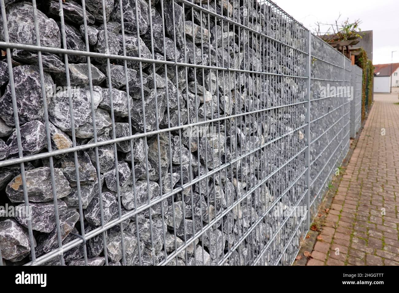 ecologically questionable garden fence made of gravel stones in a wire cage, gabion wall, Germany Stock Photo