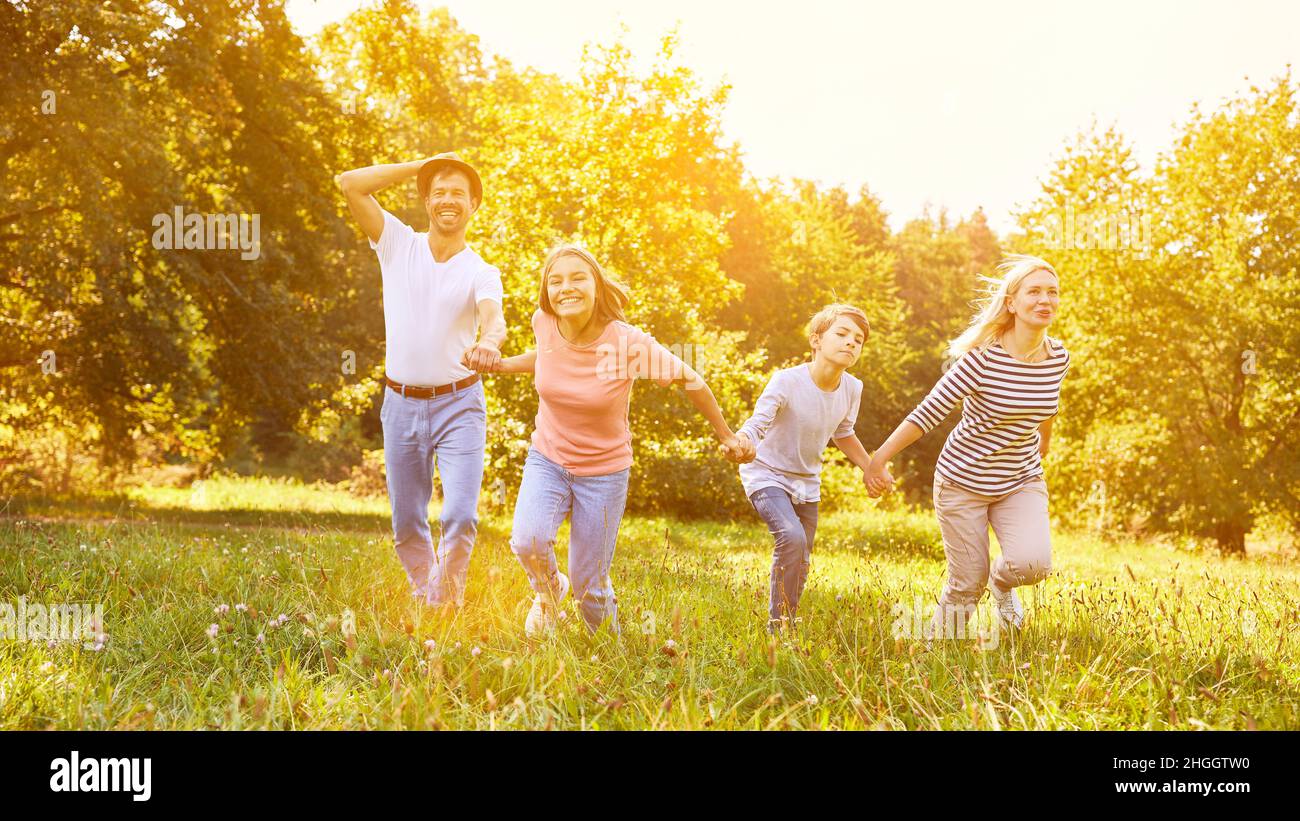 Family with two children holding hands while exercising in the garden in summer Stock Photo