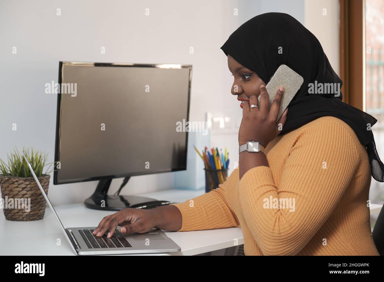 Young muslim woman calling while working from home office. Stock Photo