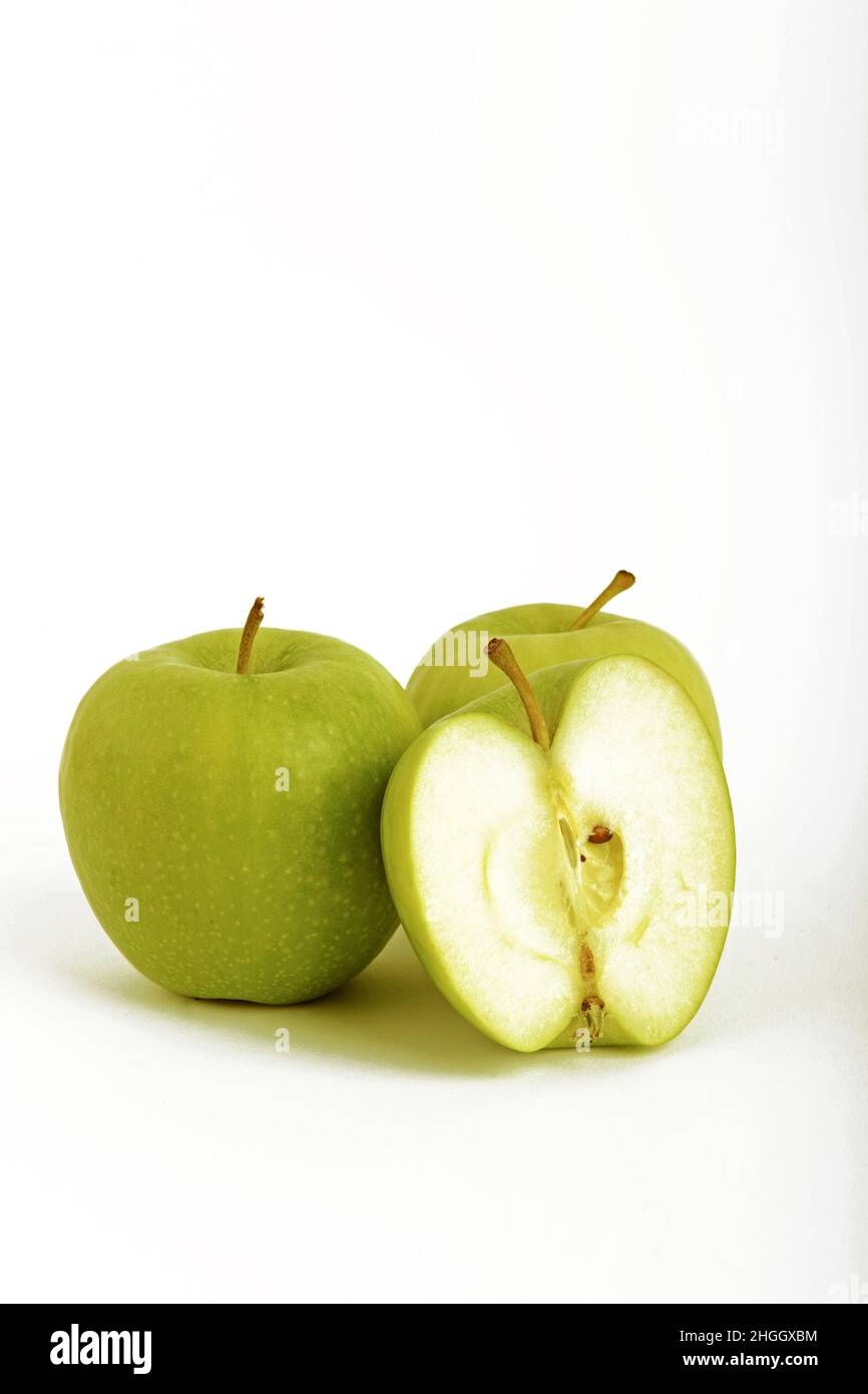 apple (Malus domestica), two fresh green apples with one halved apple, Granny Smith Stock Photo