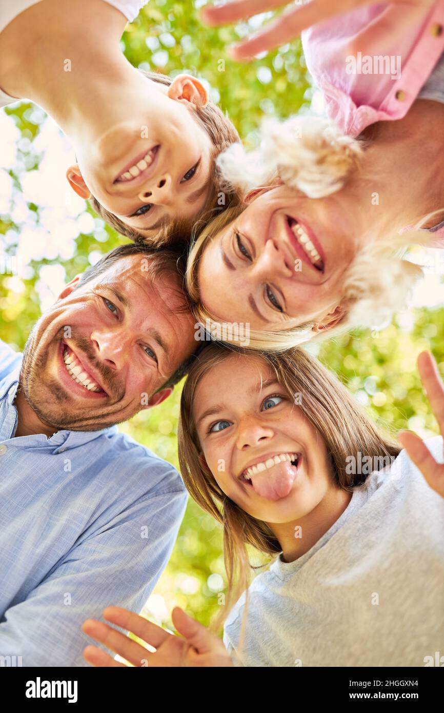 Girl cheekily sticks out tongue and fools around with brother and parents Stock Photo