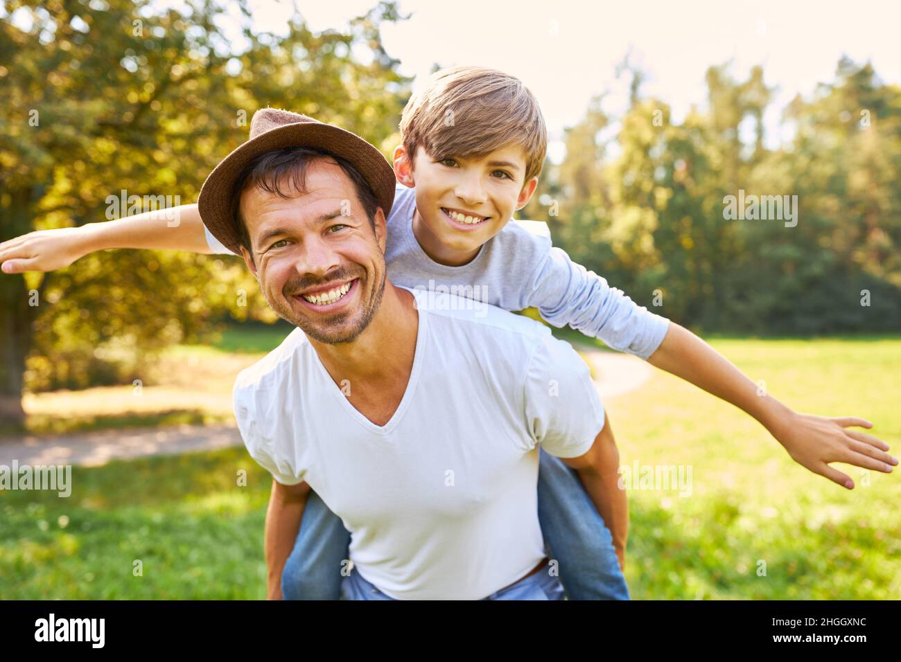 Happy father carries his son piggyback in the park in nature in summer ...