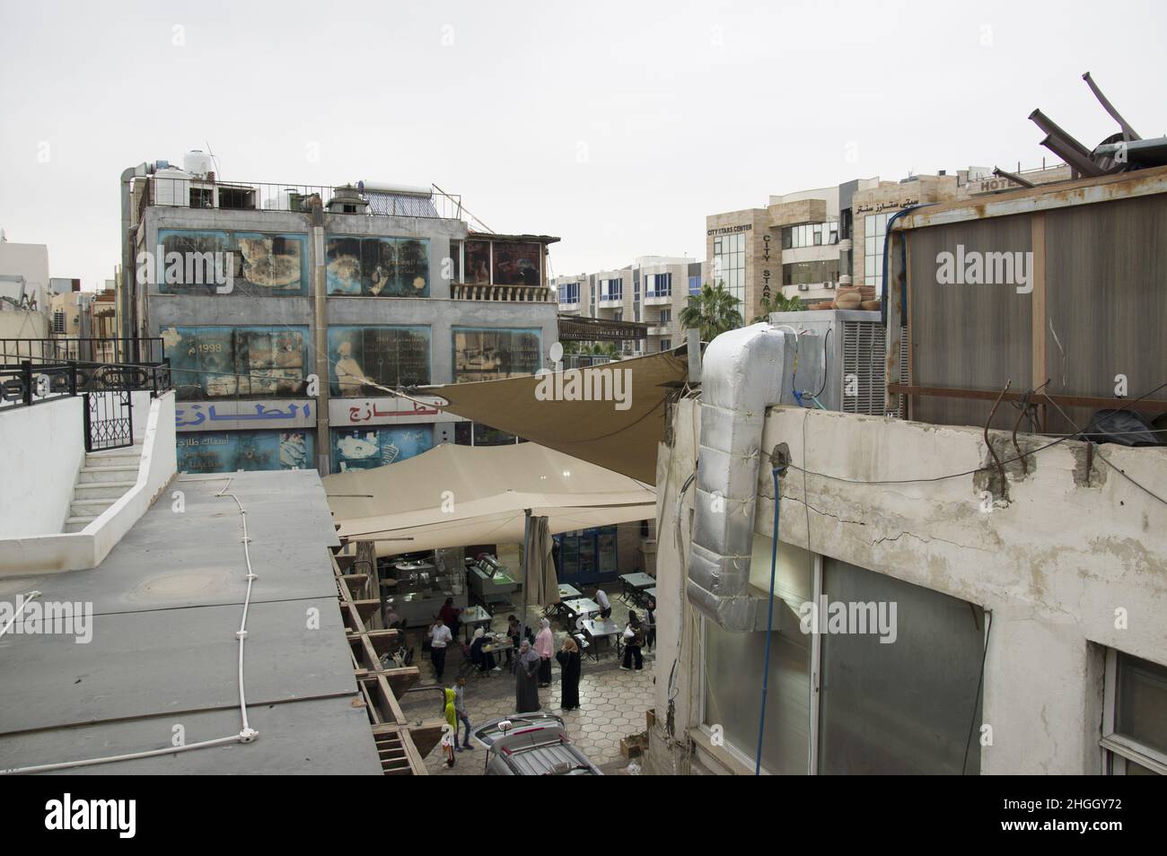Faded and windswept billboards on a building in Aqaba Jordan depicting bread making and a restaurant and Arabic writing and torn awnings. Stock Photo