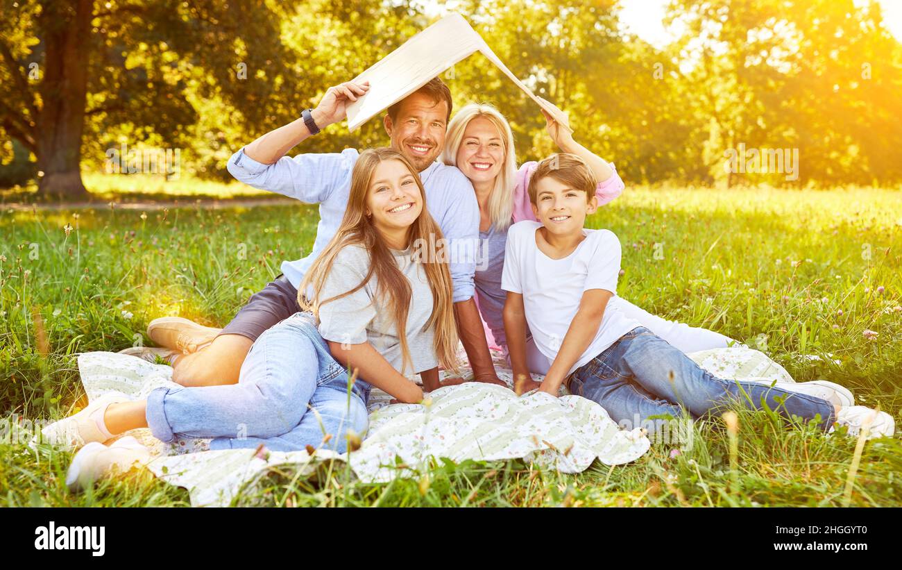 Happy family in the countryside with children and roof over their heads as house building or house buying concept Stock Photo