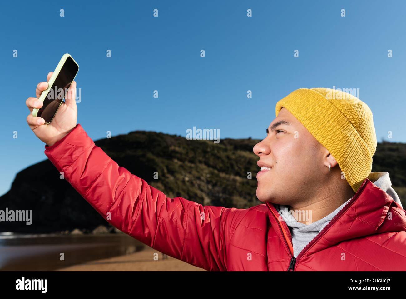 Young hispanic man wearing winter clothes taking a selfie Stock Photo