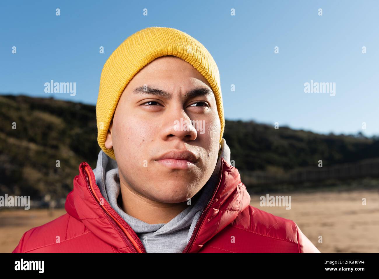 Portrait of focused hispanic man wearing a yellow hat at the beach Stock Photo