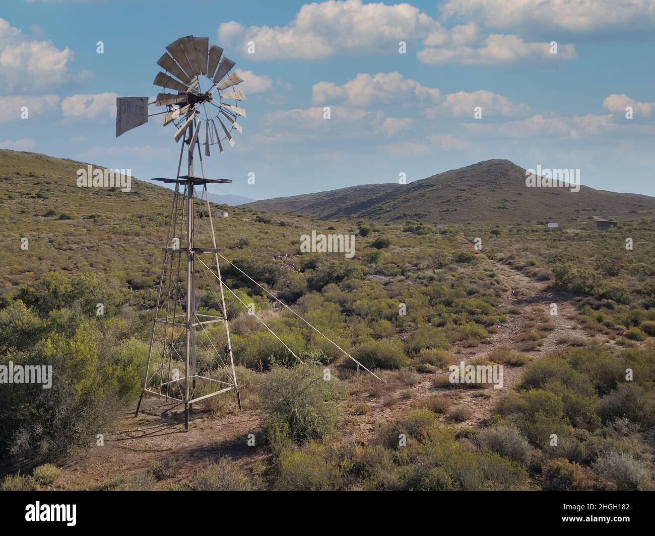 Windmill and water pump in dry landscape Stock Photo